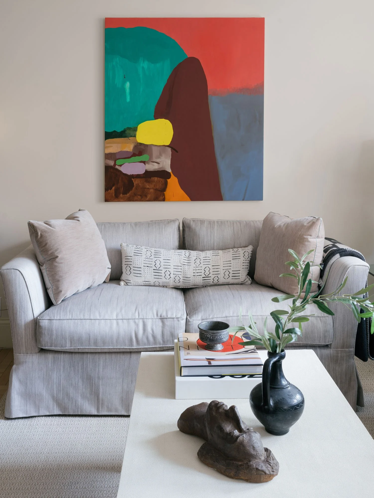 New York City interior design by Elizabeth Hartz Interior Design featuring a neutral sofa, sculptural coffee table, curated books and ceramics, and large-scale abstract artwork in a layered living space.