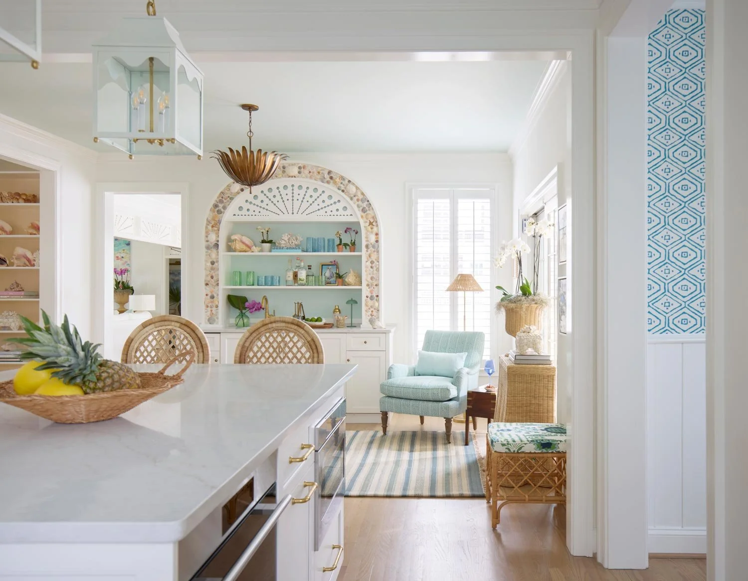 Elizabeth Hartz interior designer Virginia Beach oceanfront kitchen and bar with white cabinetry, woven stools, coastal textures, and a custom shell-detailed arch with soft blue accents and Palm Beach–inspired styling