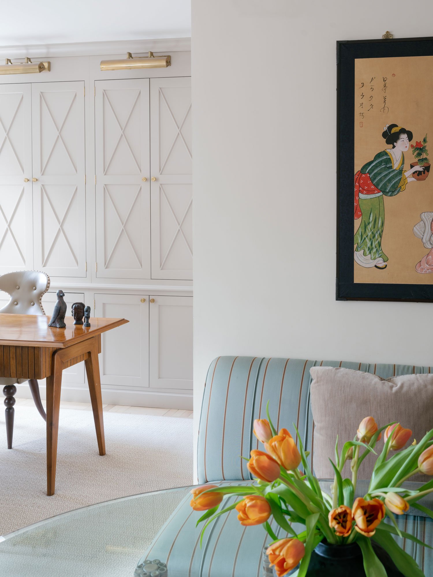 New York City interior design project by Elizabeth Hartz Interior Design featuring tailored built-in cabinetry, vintage wood desk, striped sofa, and art-forward living space styling.