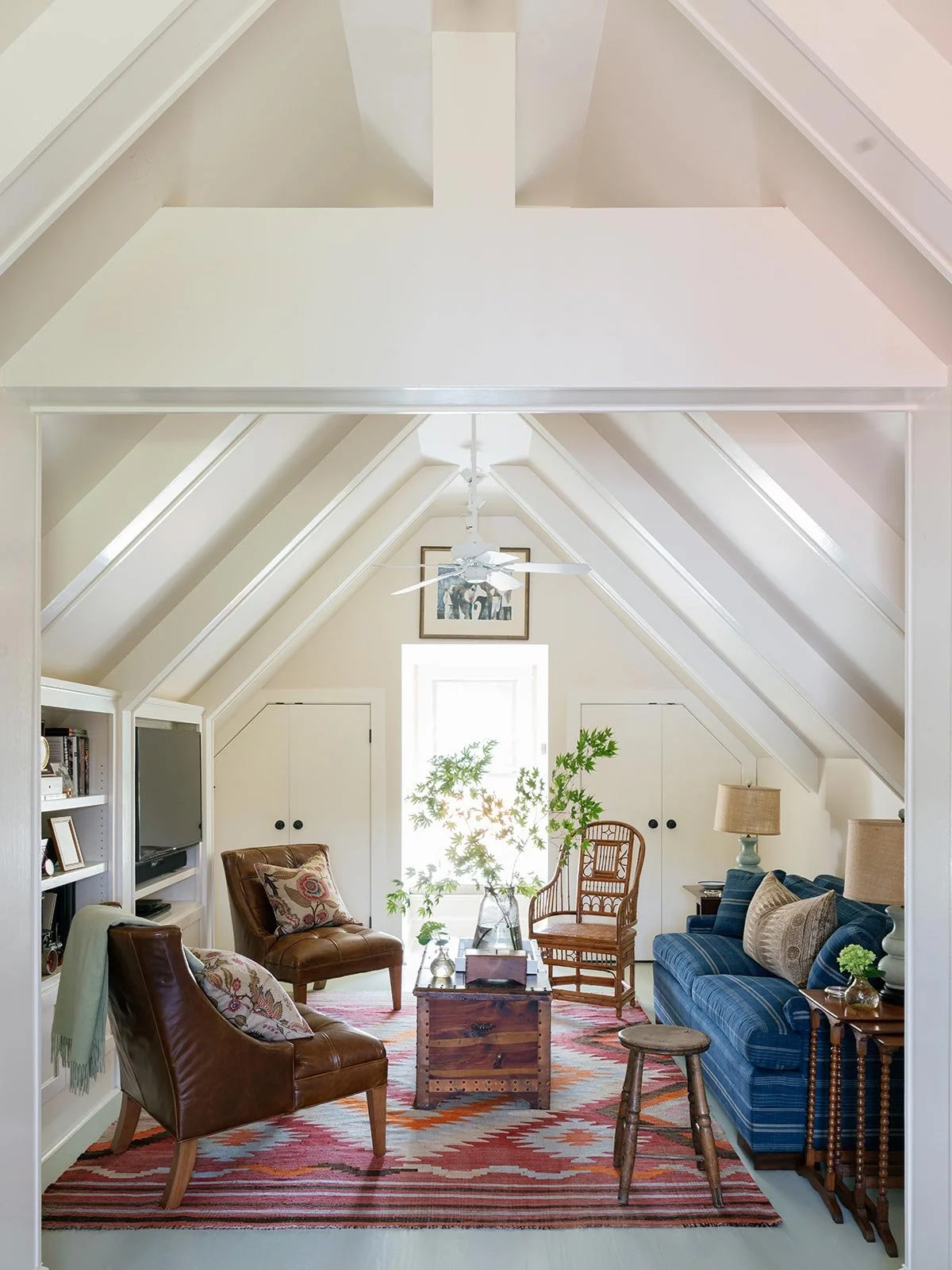 nviting top-floor game room designed by Elizabeth Hartz Interior Design at The River home in Kilmarnock, Virginia. Features vaulted ceilings, warm leather chairs, a blue sofa, patterned rug, and natural light for a relaxed coastal retreat with collec