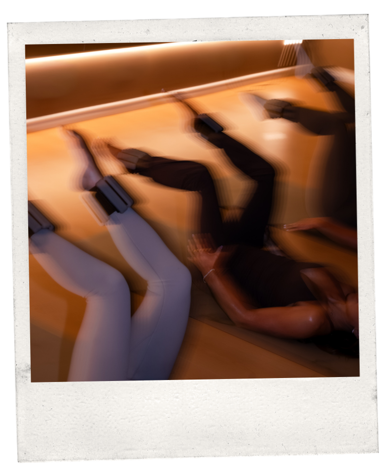 A woman lying on her side on a tanning bed with her legs elevated, wearing white leggings and a black top.