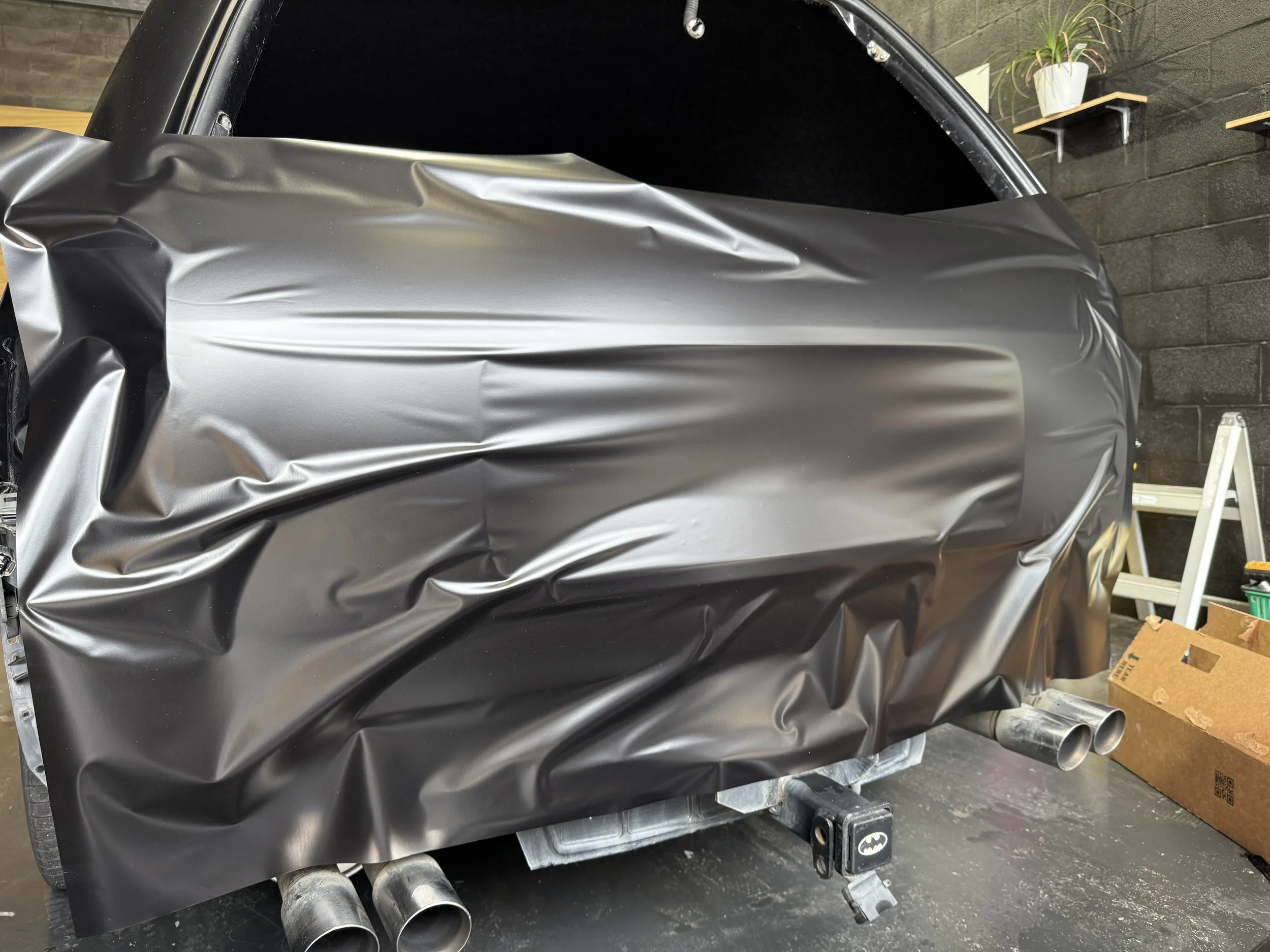 A car halfway through being wrapped in Avery Dennison Satin Obsidian Black Supreme Wrapping Film.