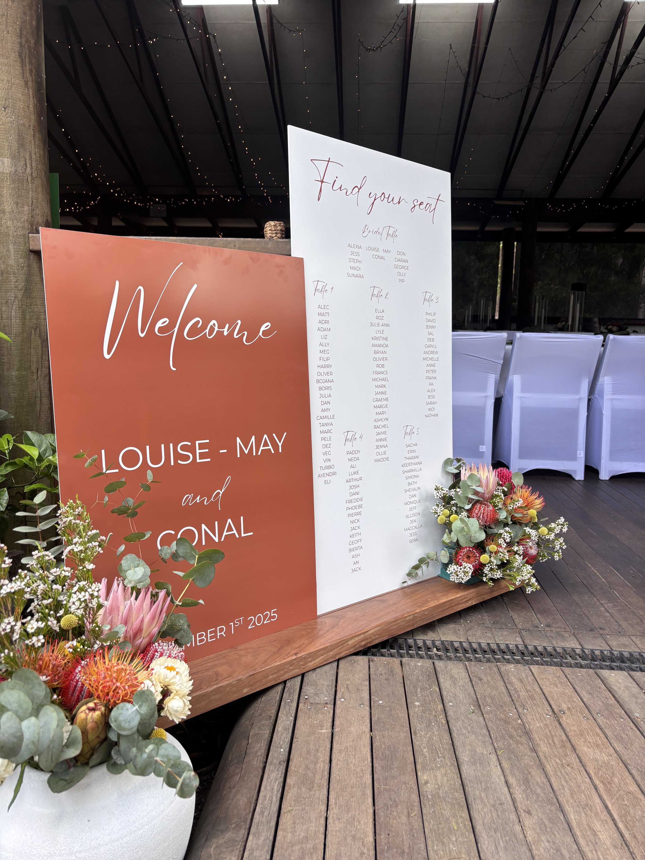 Wedding seating chart & welcome signs with floral arrangements at a reception venue.
