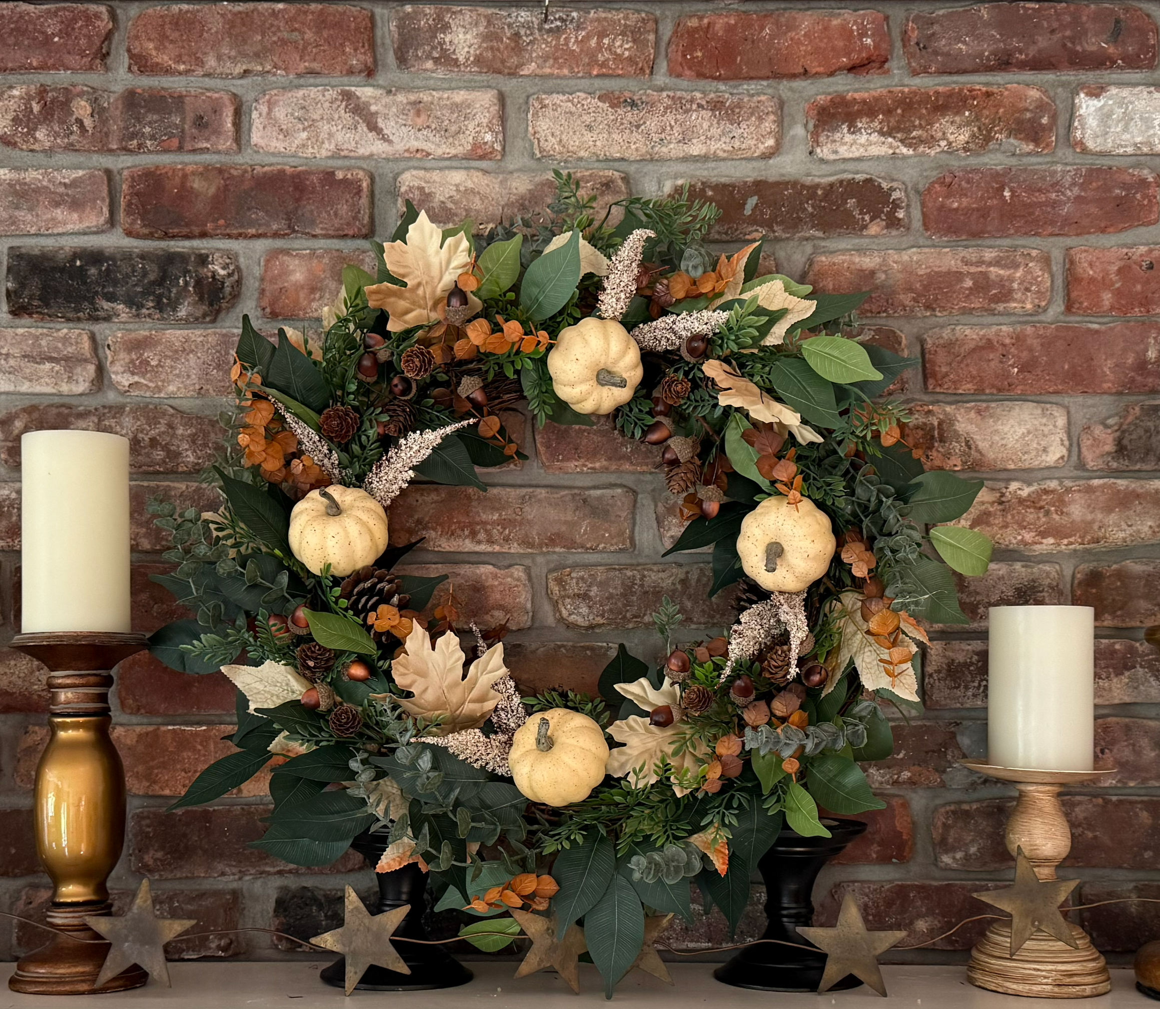 A custom autumn harvest wreath to transition your home decor from early fall straight through Thanksgiving. Hand-crafted with warm fall leaves, realistic acorns, pinecones, and mini white pumpkins, this versatile piece looks stunning styled as an int
