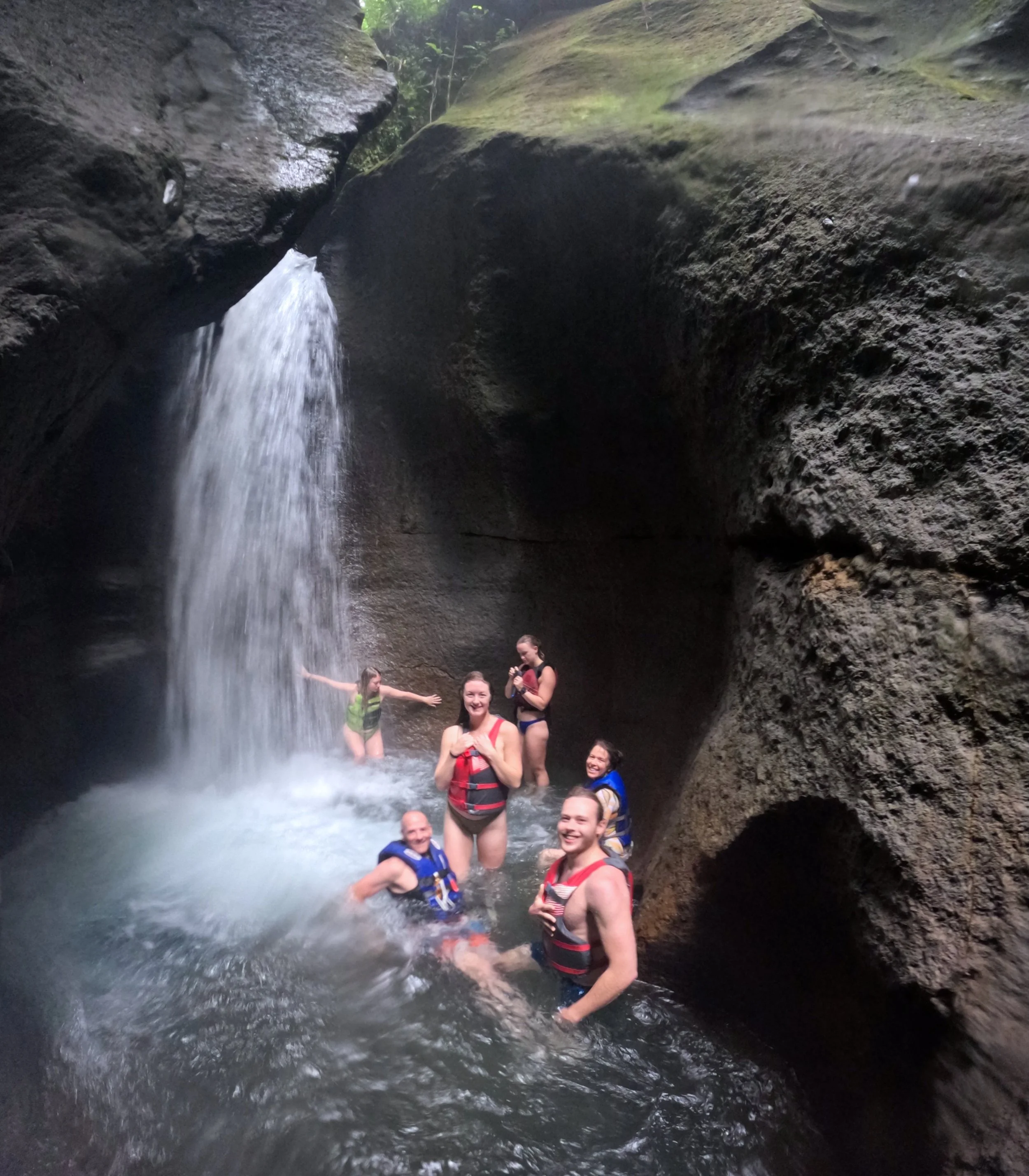 Group of people enjoying a waterfall in a rocky cave