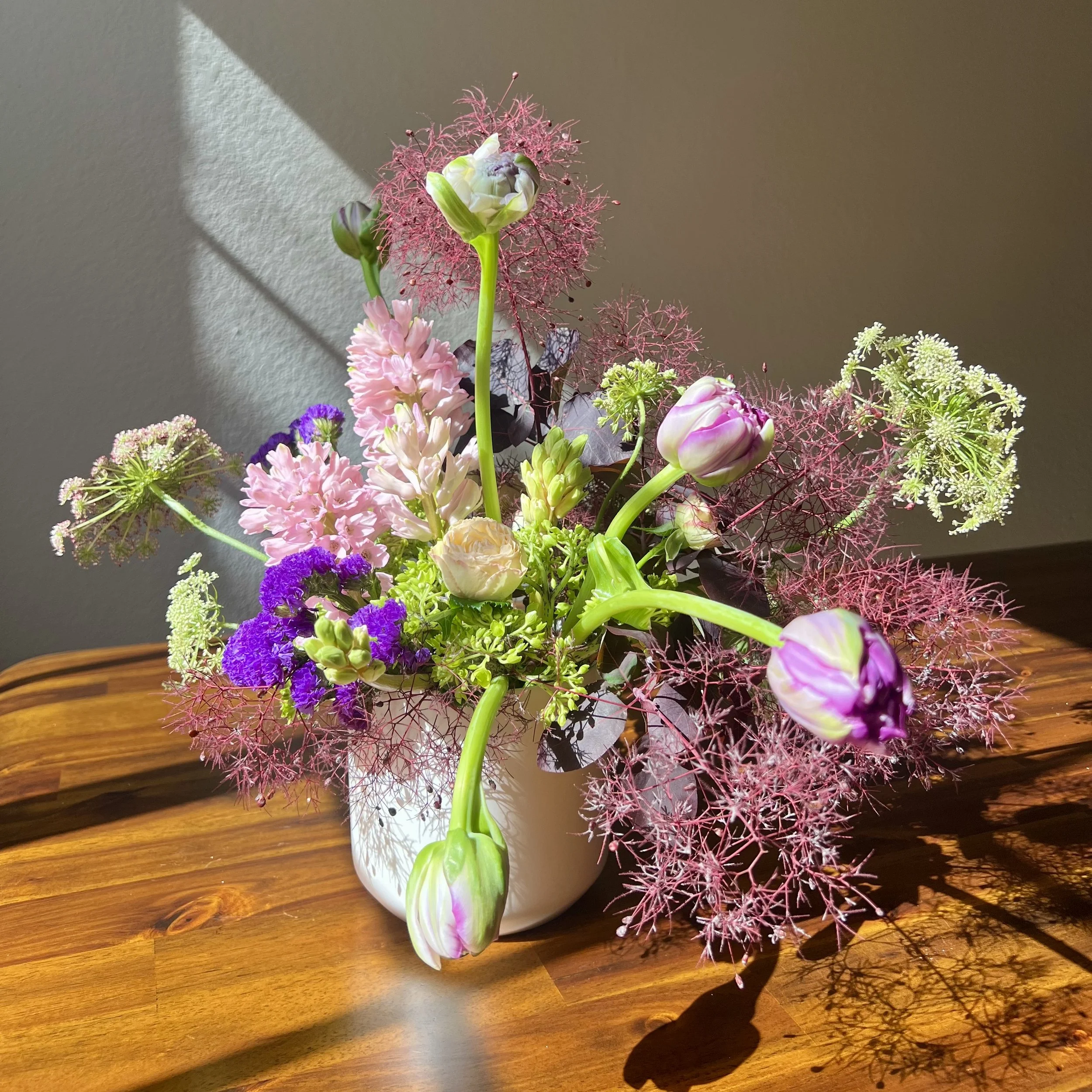 Loose, airy Mother’s Day bouquet with tulips and roses in a ceramic vase, designed in a natural garden style.