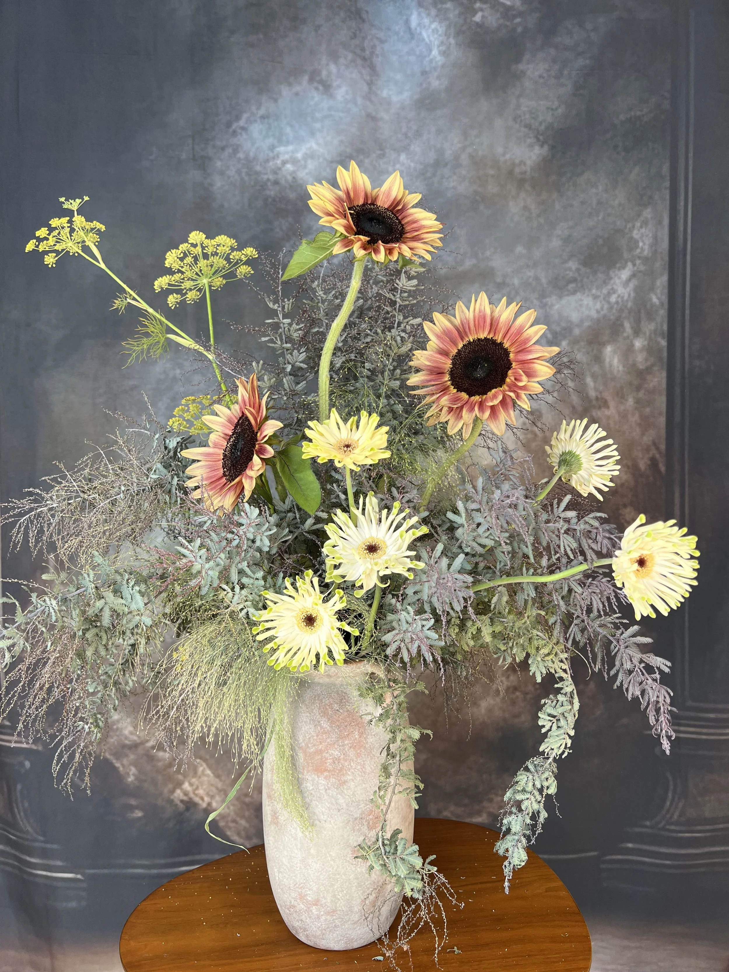 Sunflower filled tall floral arrangement with a lot of movement.