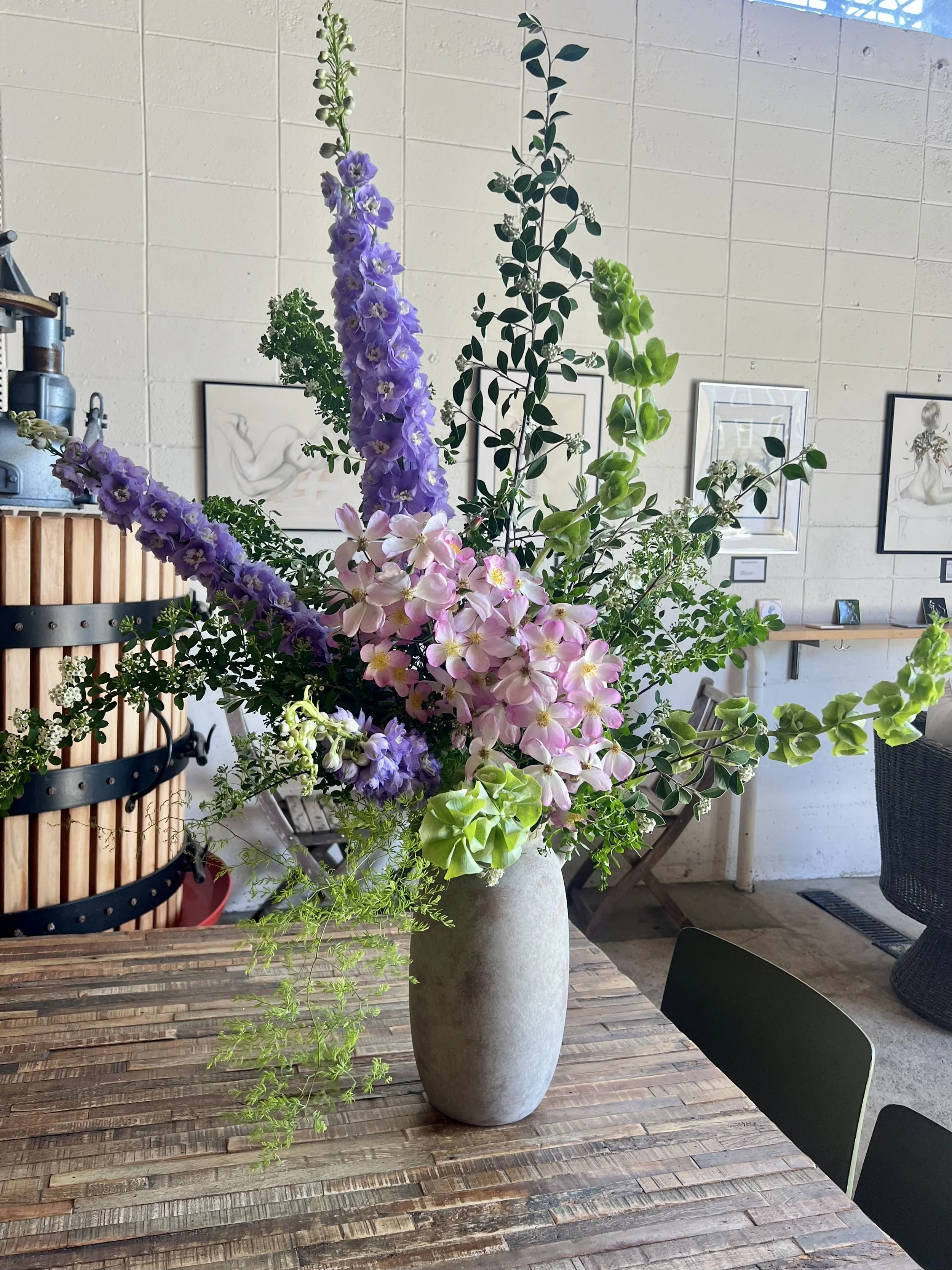 Organic design restaurant bar floral arrangement featuring tall sculptural branches, lush seasonal blooms, and layered greenery creating a whimsical, garden-inspired atmosphere.