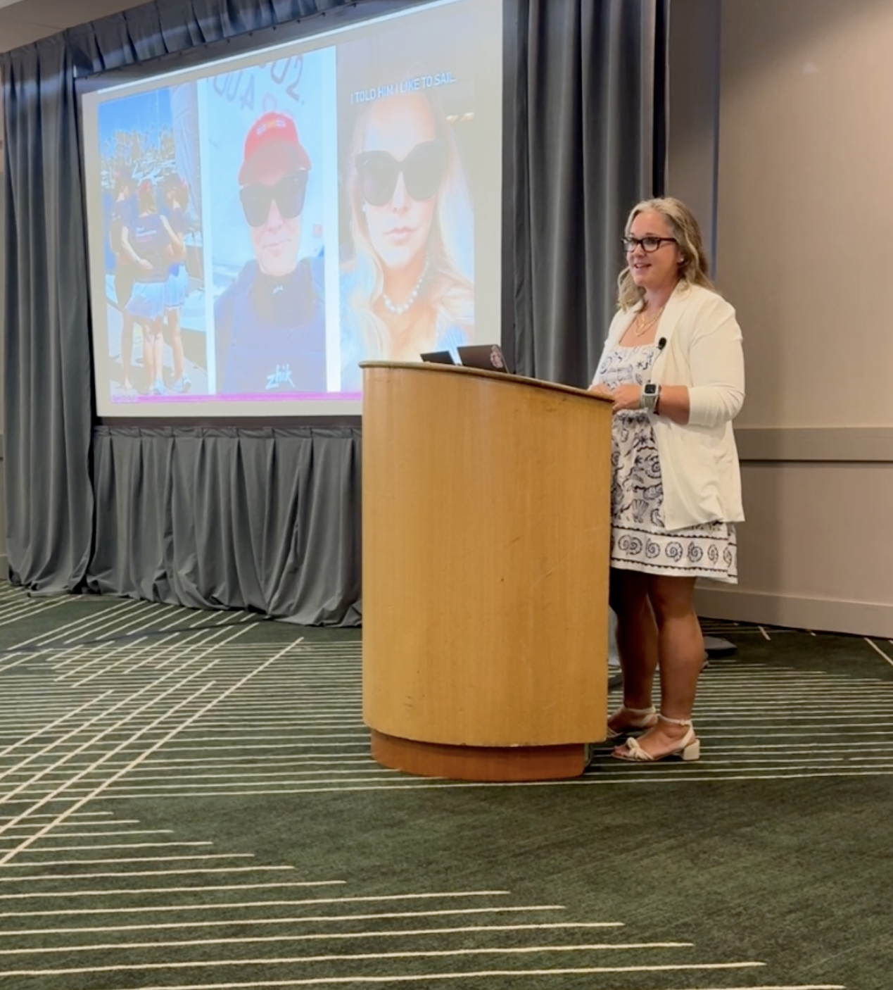 Lauren Wilson stands at a podium delivering a motivational talk, speaking about resilience, leadership, and her Olympic sailing journey.