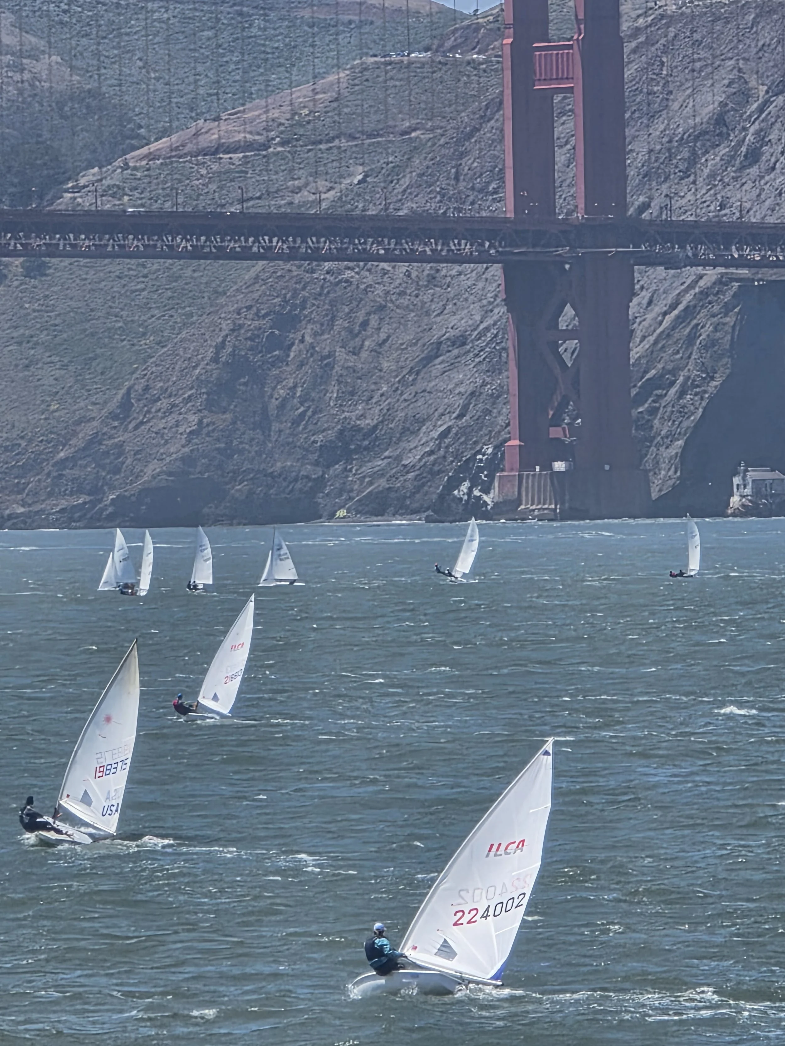Wide shot of Lauren Wilson hiking hard in heavy wind on San Francisco Bay as she drives her ILCA 6 upwind.