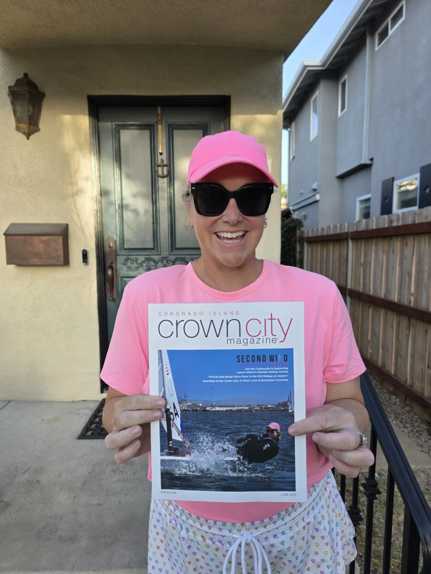 Lauren holding the June 2026 issue of Crown City Magazine which features her Olympic sailing campaign's story on the cover of the magazine. The cover photo is Lauren sailing her ILCA 6 sailboat in the Pacific Coast Championships