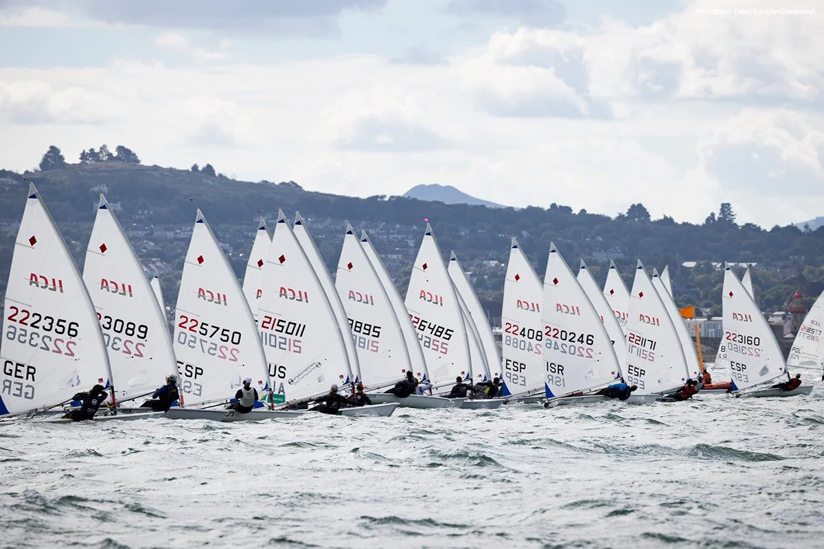 ILCA sailboats on the starting line of a regatta, racing to the future