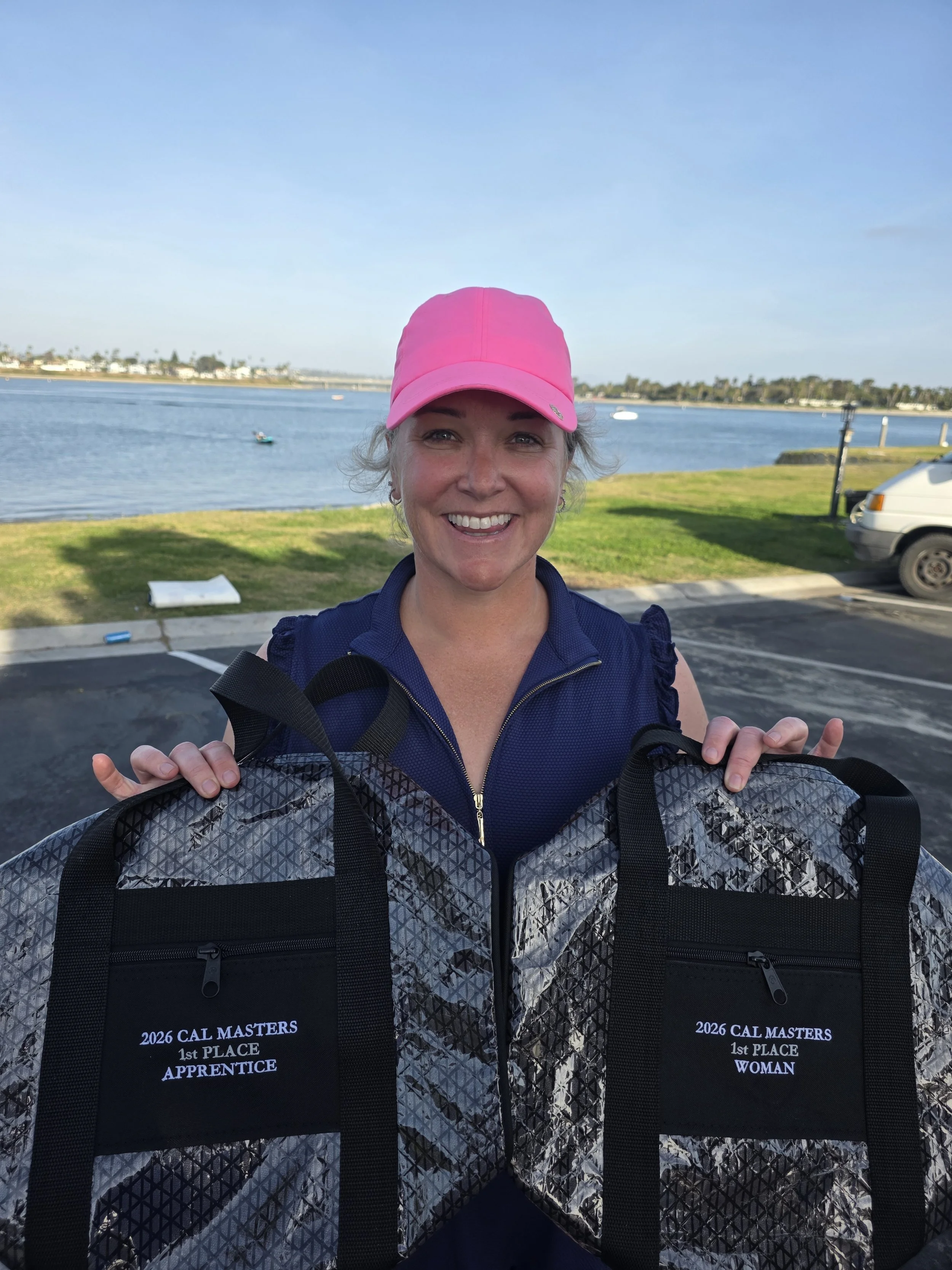 Woman in pink hat showing her two trophies as the top woman and top apprentice sailor.