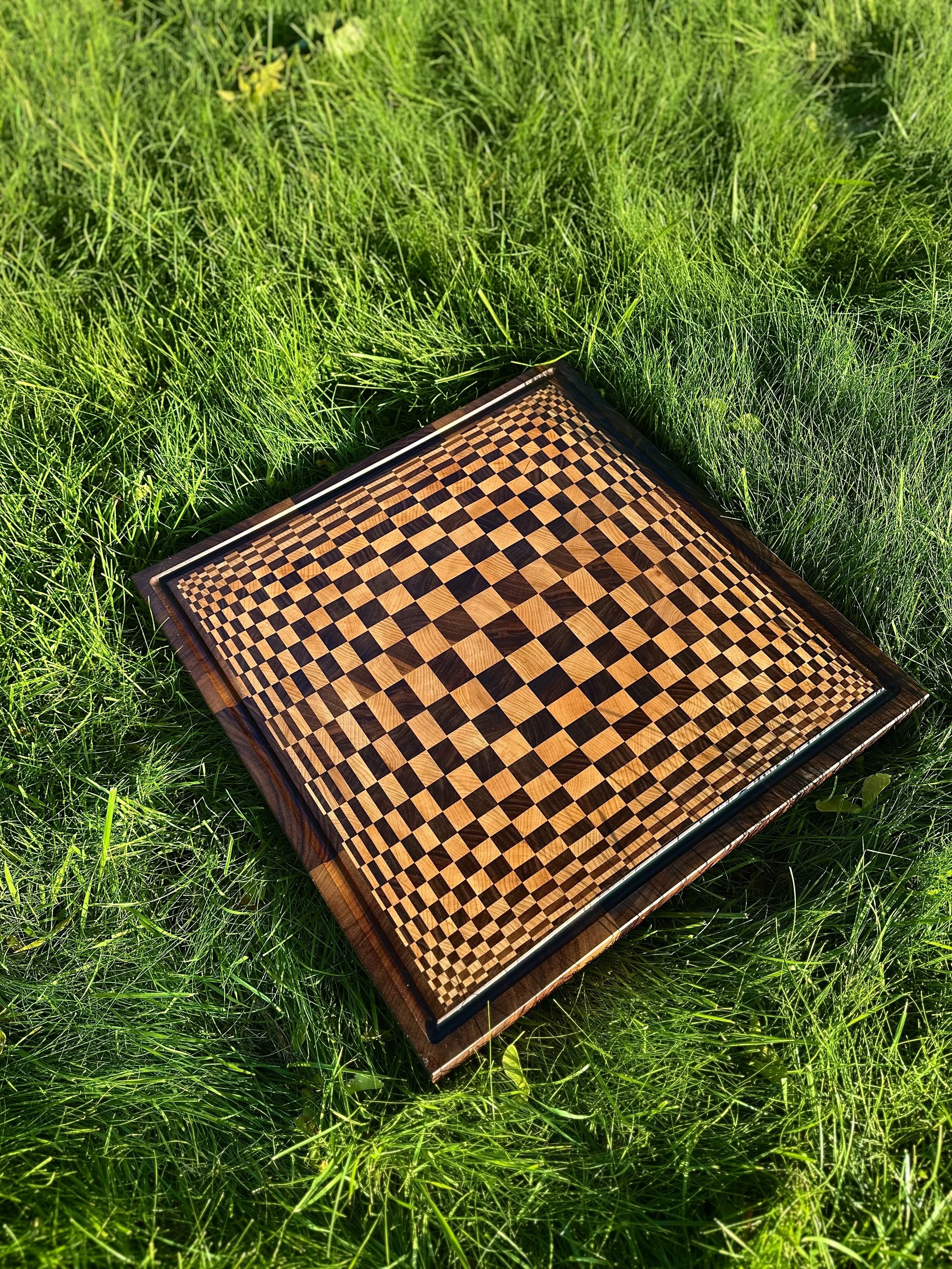 Wooden chessboard with a checkered pattern lying on green grass