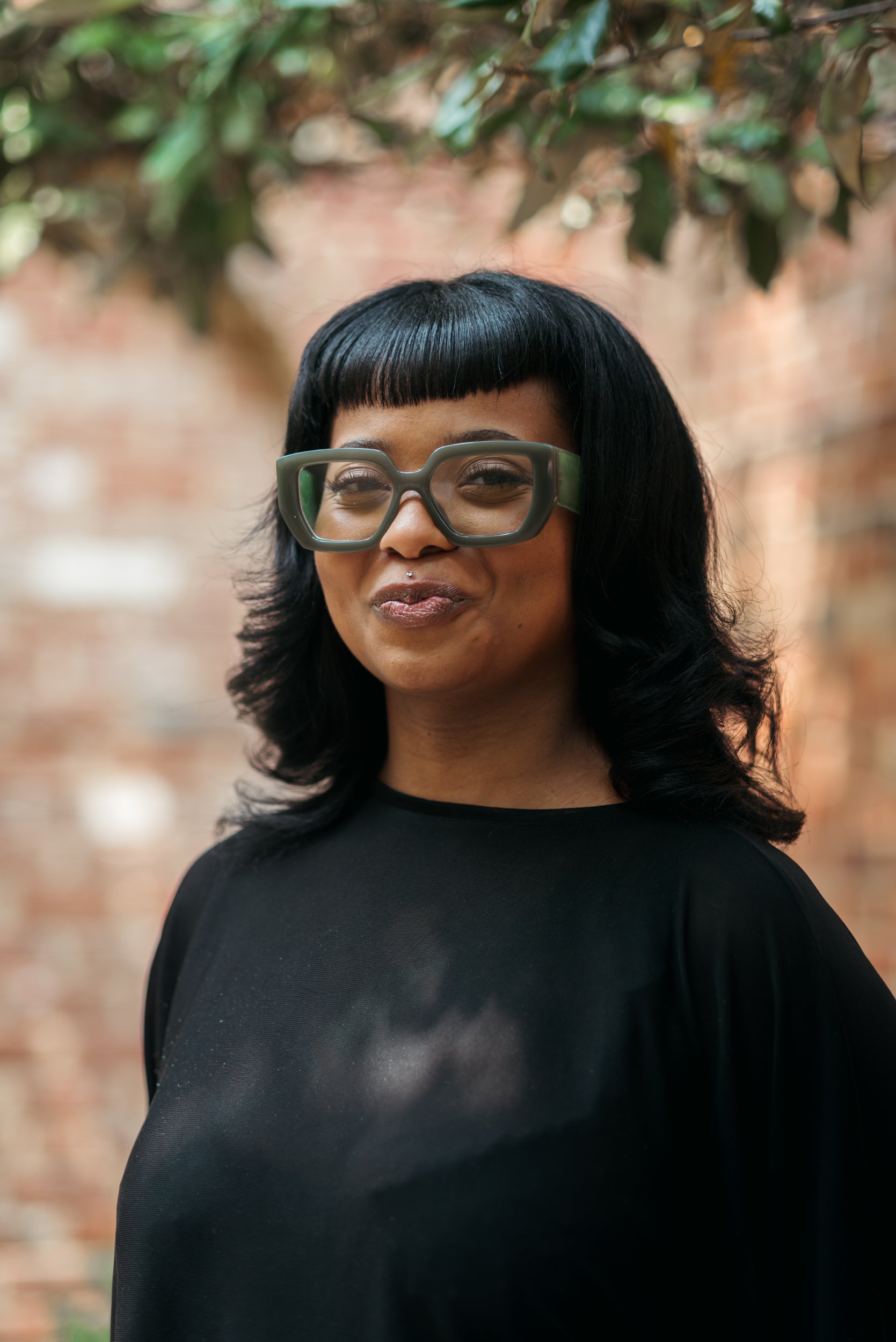 A woman with glasses smirks at the camera.