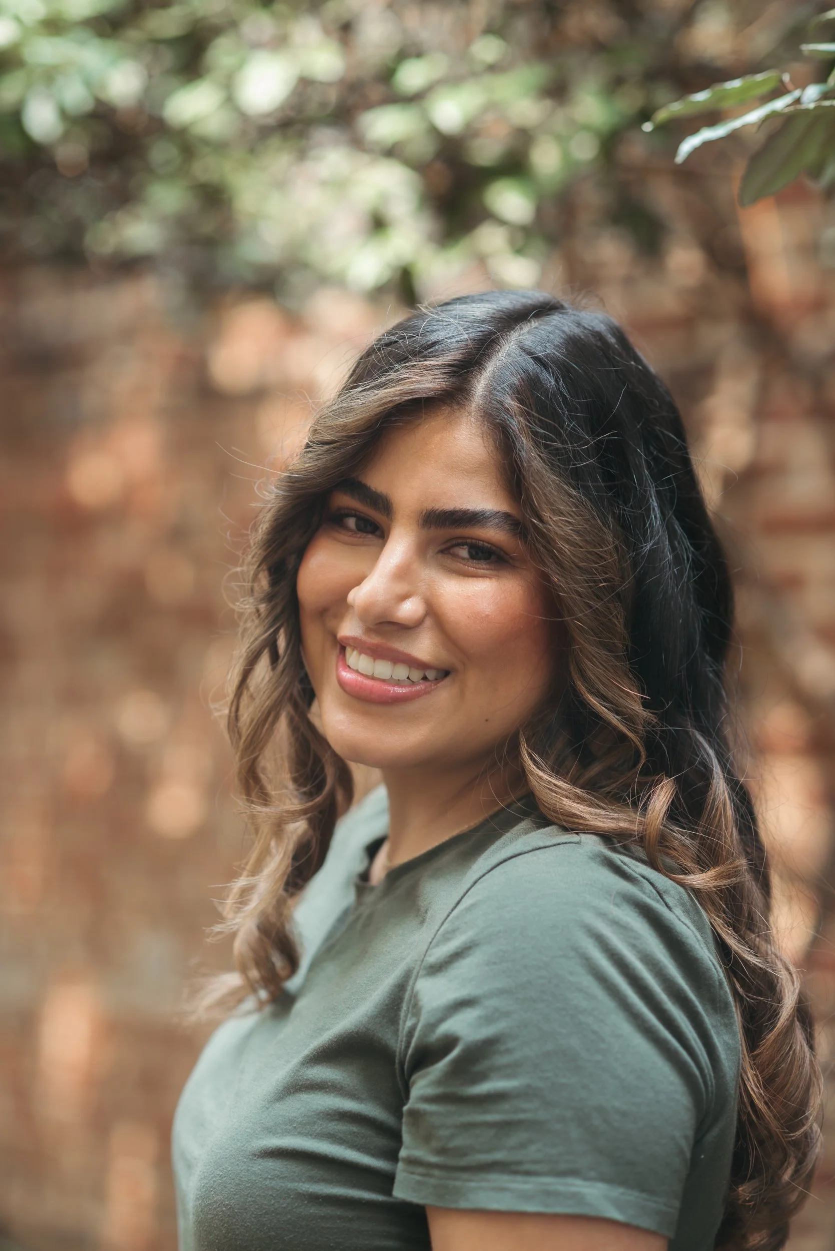 A woman looks over her shoulder and smiles at the camera in this environmental headshot.