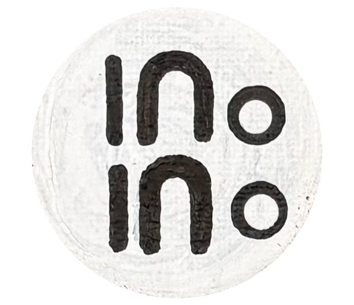 A white circular object with black logo or text reading 'ino' printed twice upside down and right-side up. Aboriginal community art