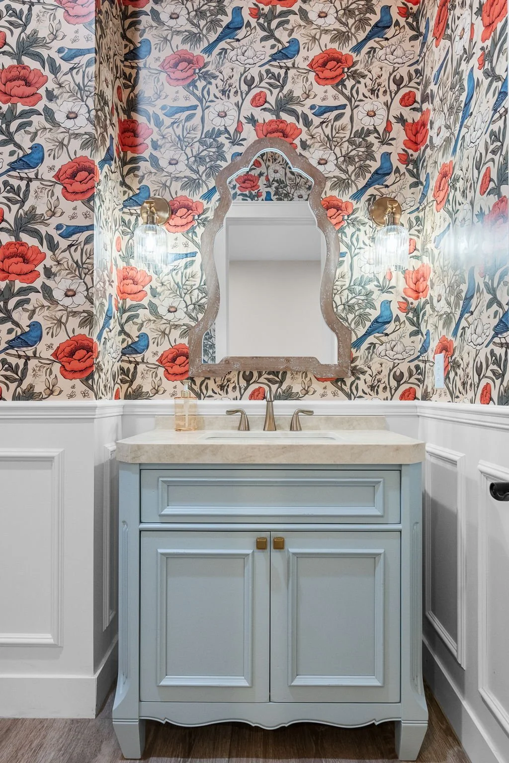 This custom bathroom vanity features Shiloh Custom Cabinetry painted in the striking Niebla Azul finish, complemented by sophisticated honey bronze hardware from Top Knobs. The combination of soft blue tones and warm metallic accents creates a refine
