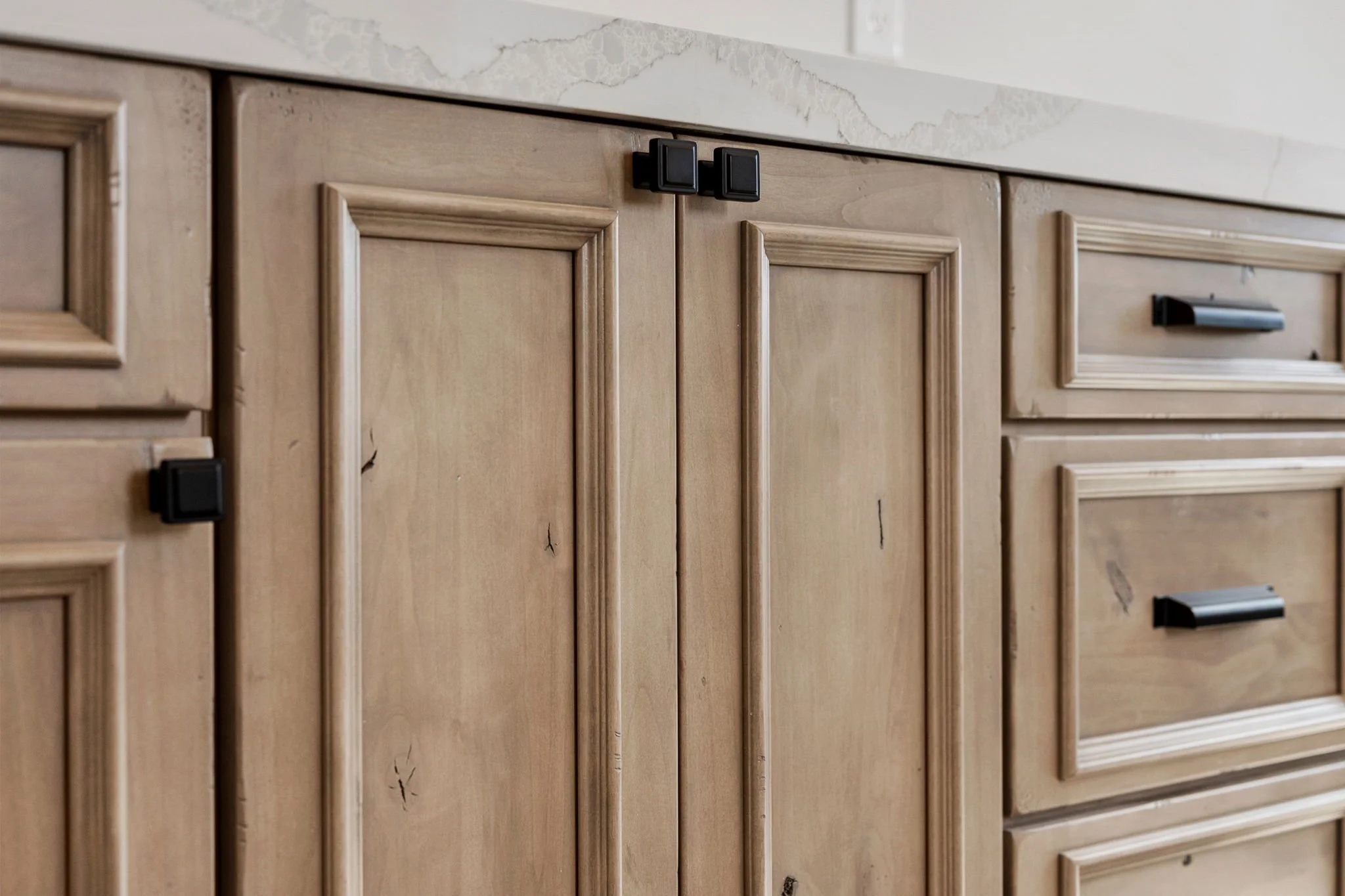 This custom vanity showcases Shiloh Custom Cabinetry crafted from knotty, high-character alder and finished in the popular “White Sands” stain. Accented with bold black hardware from Top Knobs, this design delivers a warm, rustic-modern aesthetic wit