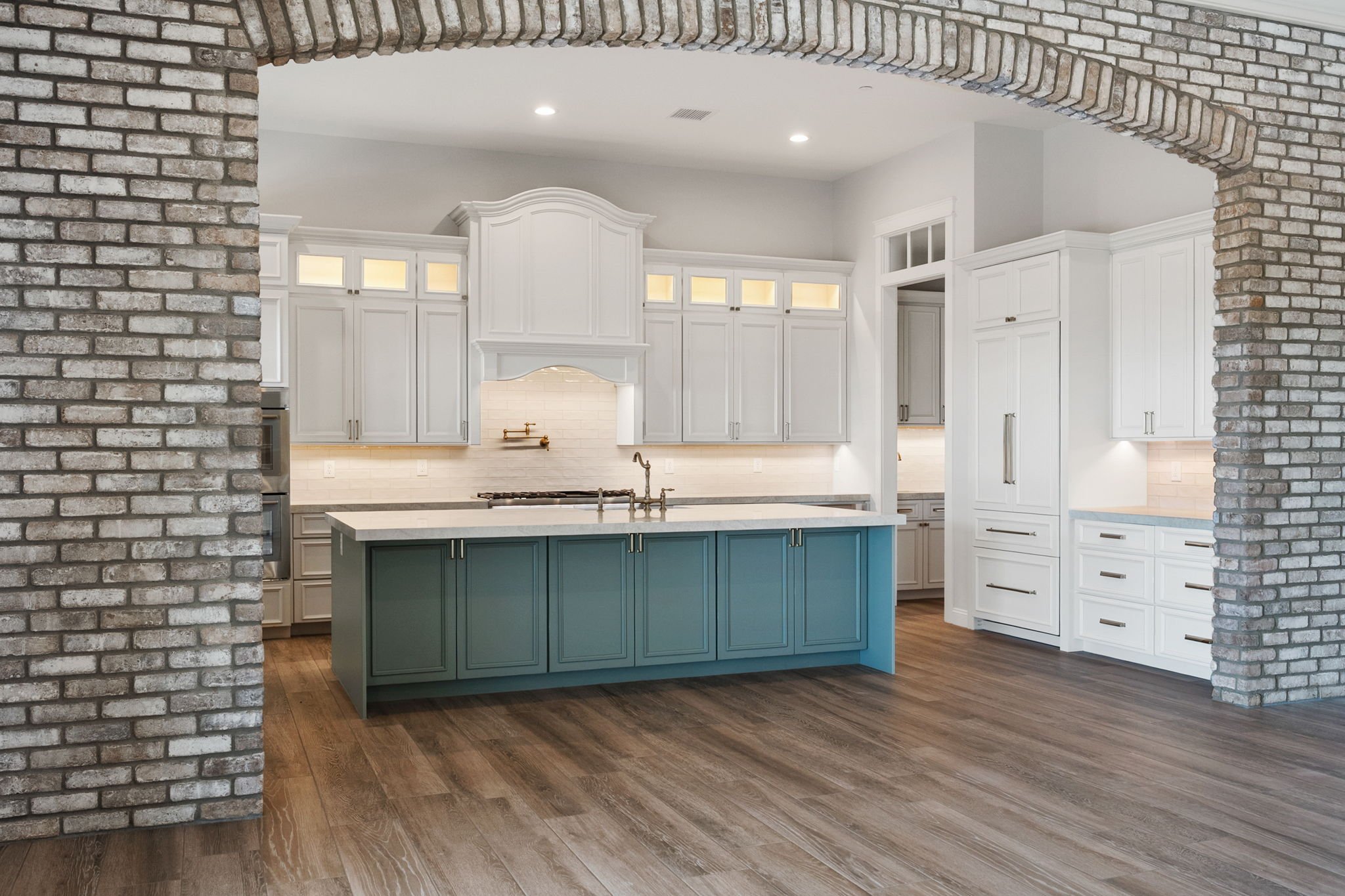 This custom kitchen island showcases Shiloh Custom Cabinetry painted in Evergreen Fog, a modern, nature-inspired color that adds depth and character to any space. Paired with honey bronze hardware from Top Knobs, this island serves as a bold focal po
