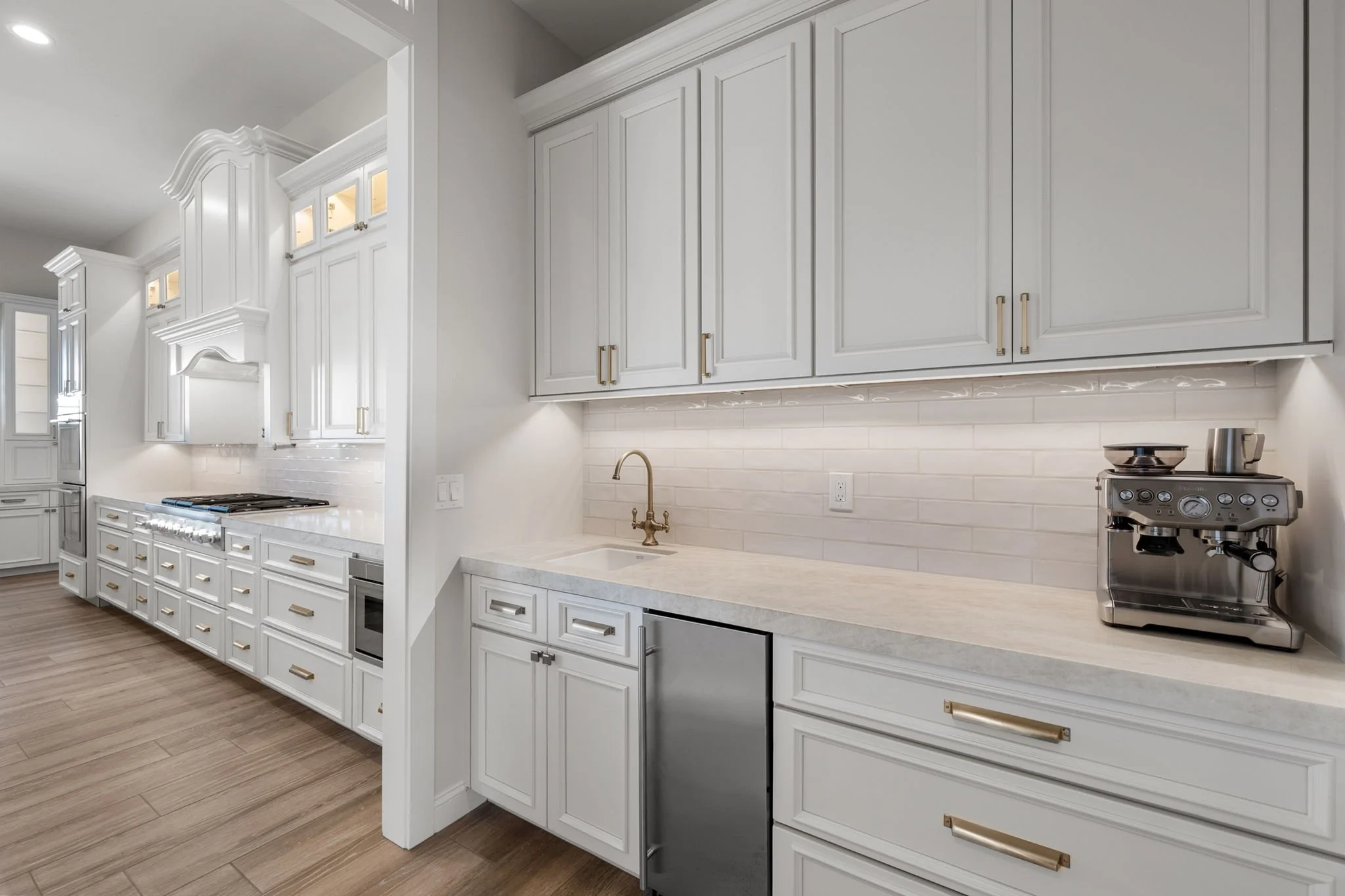This custom kitchen features premium Shiloh Custom Cabinetry in a timeless Shoji White painted finish, paired with elegant honey bronze hardware from Top Knobs. Designed for both style and durability, this kitchen highlights clean lines, warm tones, 