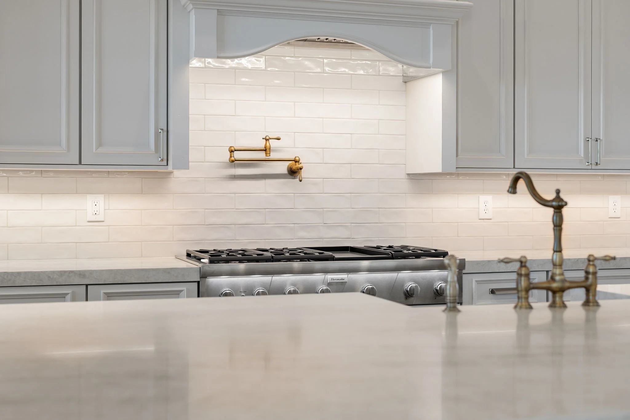 This custom kitchen features premium Shiloh Custom Cabinetry in a timeless Shoji White painted finish, paired with elegant honey bronze hardware from Top Knobs. Designed for both style and durability, this kitchen highlights clean lines, warm tones, 