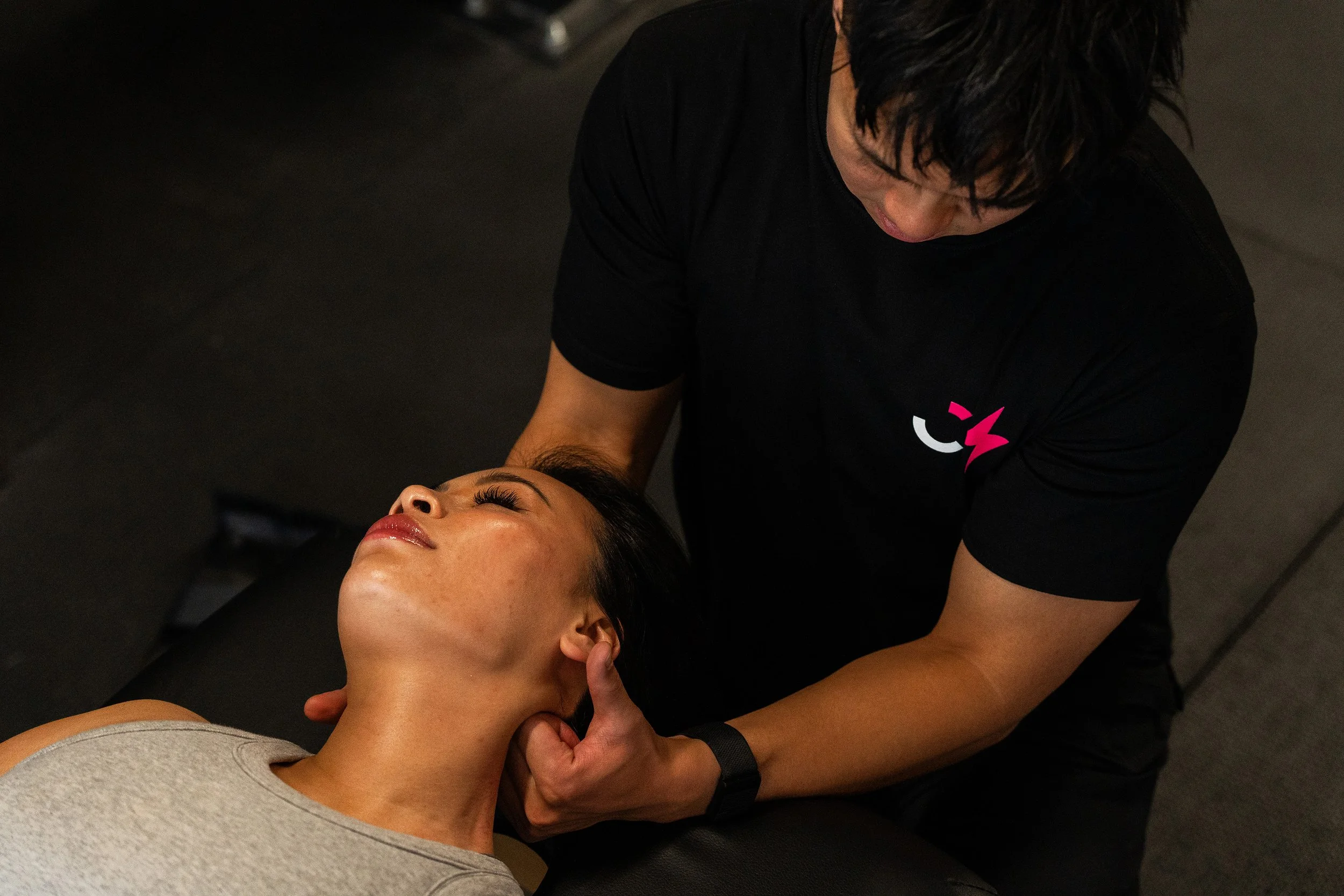 A man providing a chiropractic adjustment to a woman lying on a massage table, with both appearing relaxed.