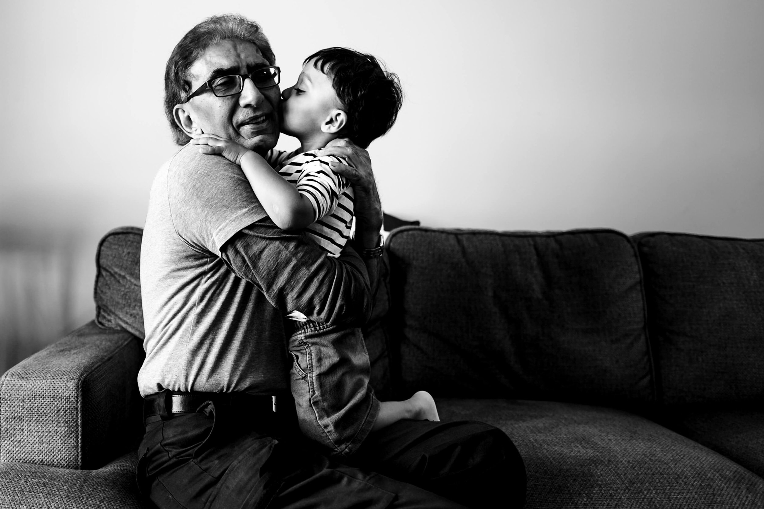 Boy kissing his grandfather on the couch.