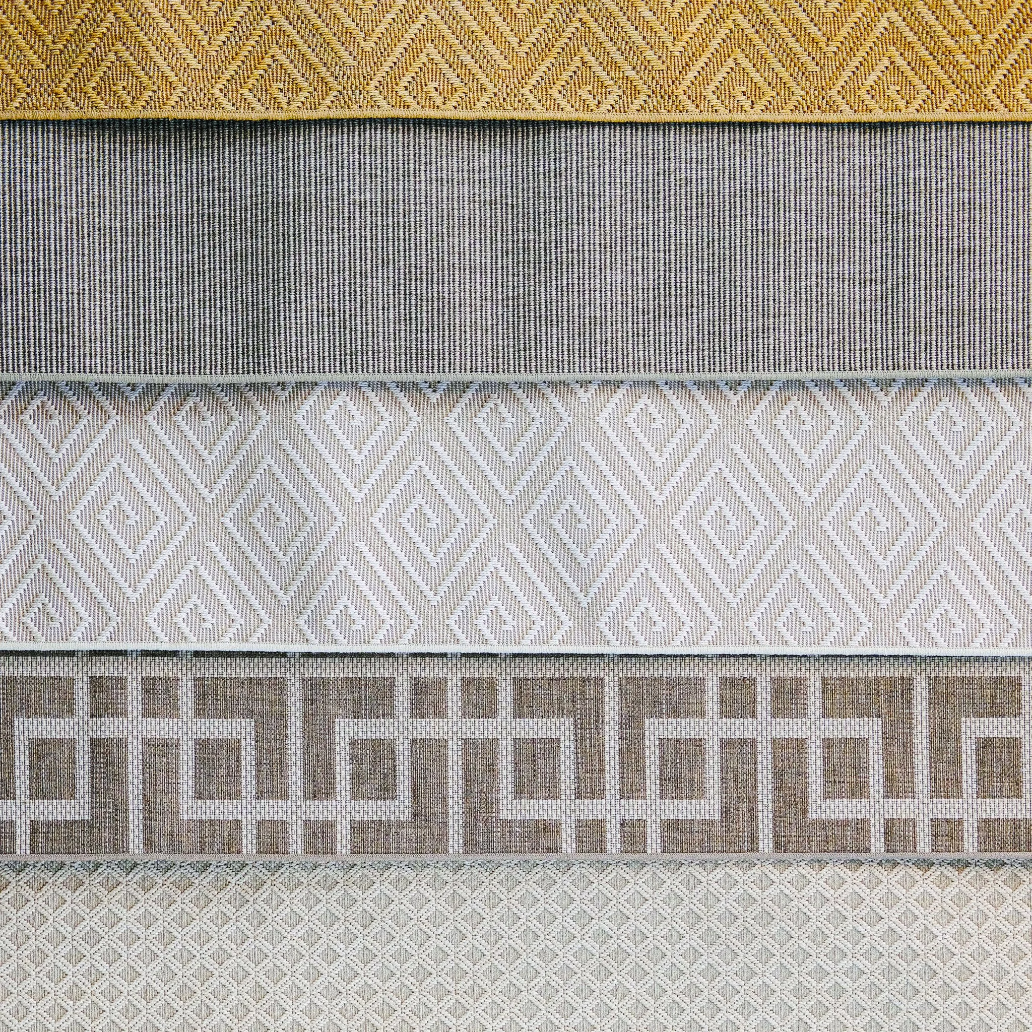 Four horizontal outdoor carpets with different intricate woven patterns, each showing geometric designs in neutral tones from top to bottom: diamond shapes, vertical lines, diamonds with smaller diamond in the center, and a grid-like pattern.