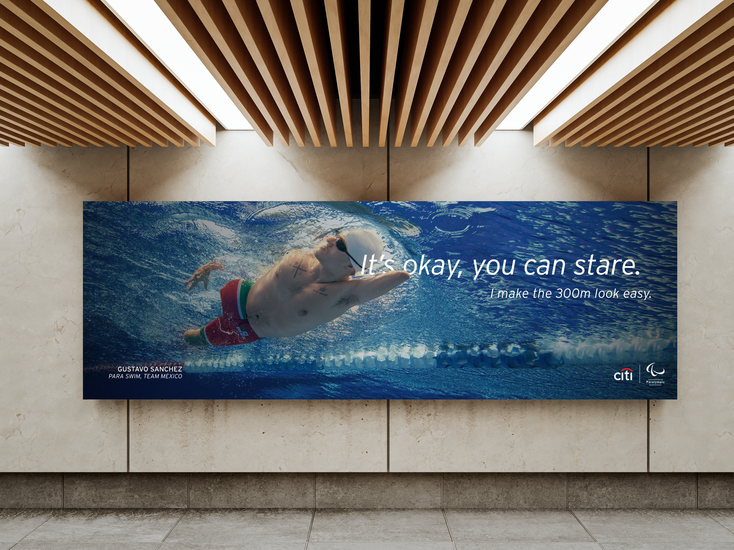 A large digital advertisement featuring a male swimmer in a swimming pool with swim goggles and red swim trunks. The text on the ad says, 'It's okay, you can stare. I make the 300m look easy.' The ad includes logos for Citi and the Paralympic Committ