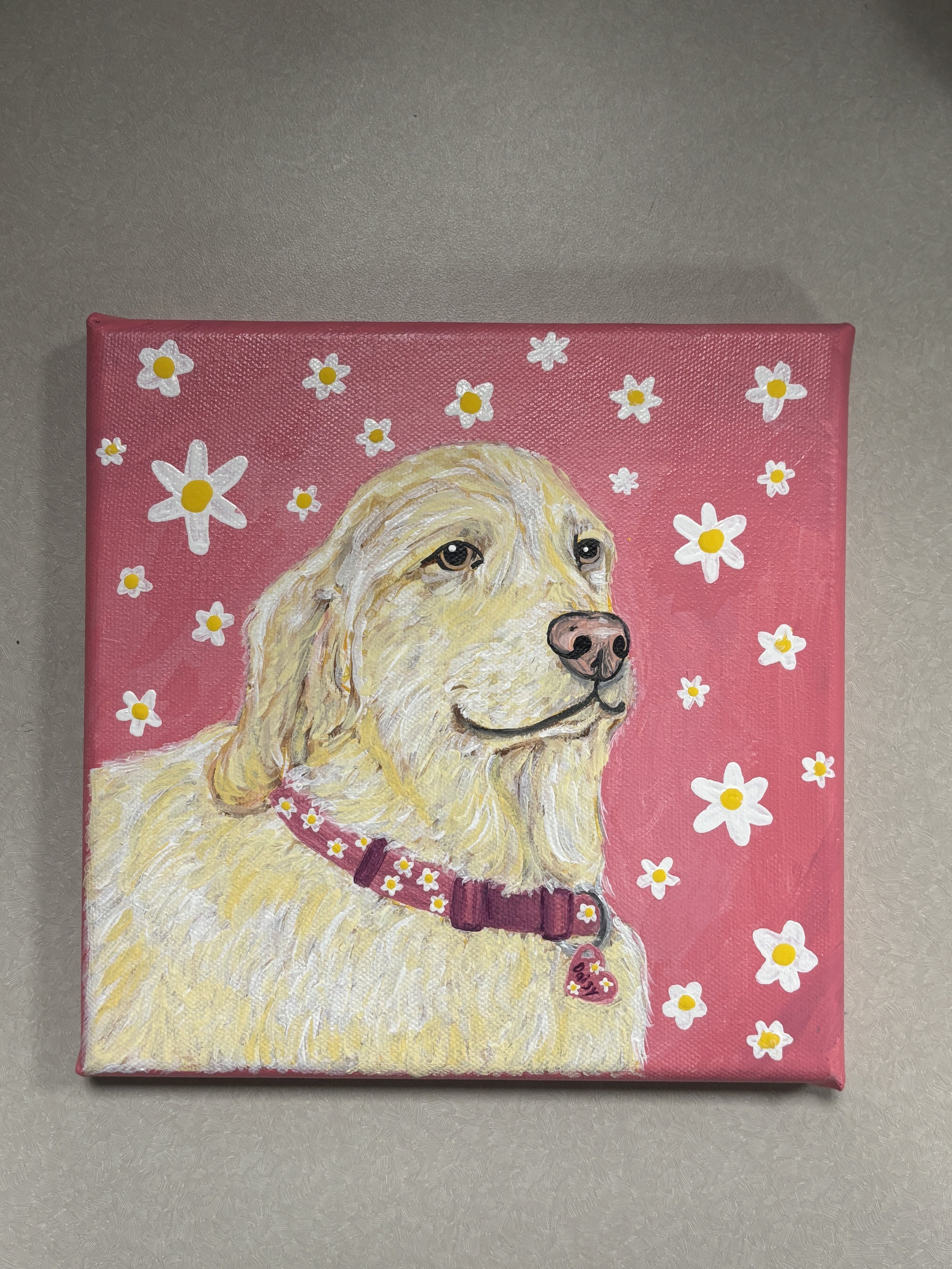 A painting of a yellow retriever dog with a pink background decorated with white flowers and yellow centers. The dog is wearing a red collar with a heart-shaped tag.