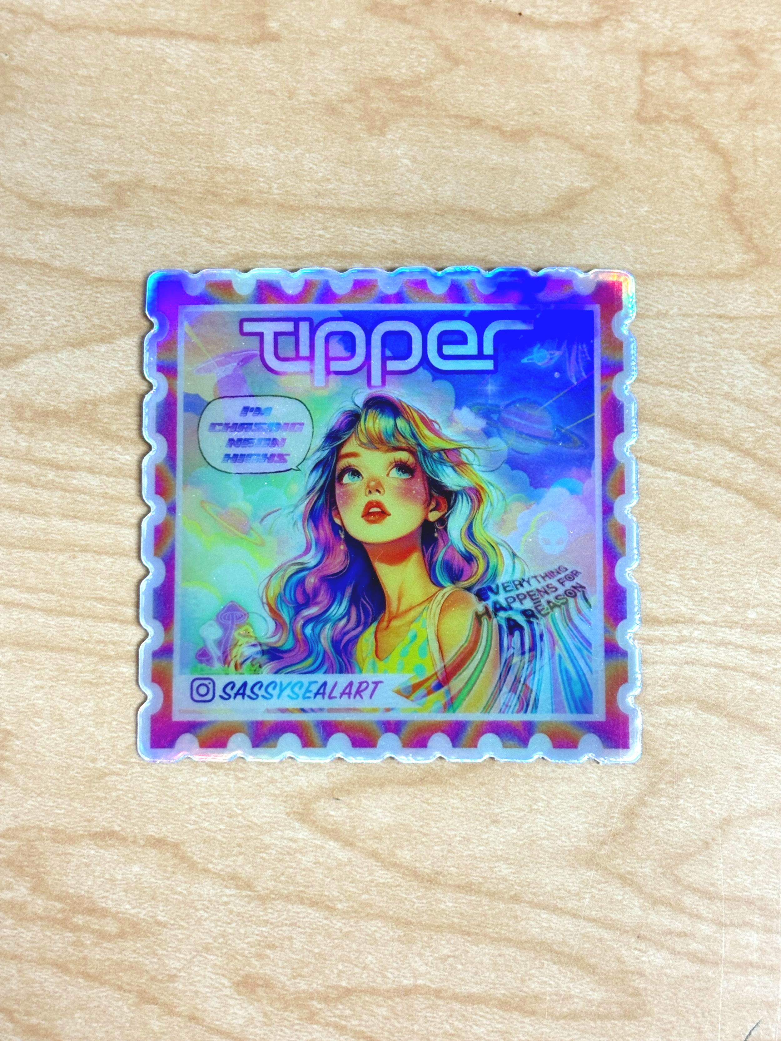 Holographic sticker featuring a woman with colorful hair, the word 'tipper' at top, and the Instagram handle '@SASSYSEALART' at bottom left.