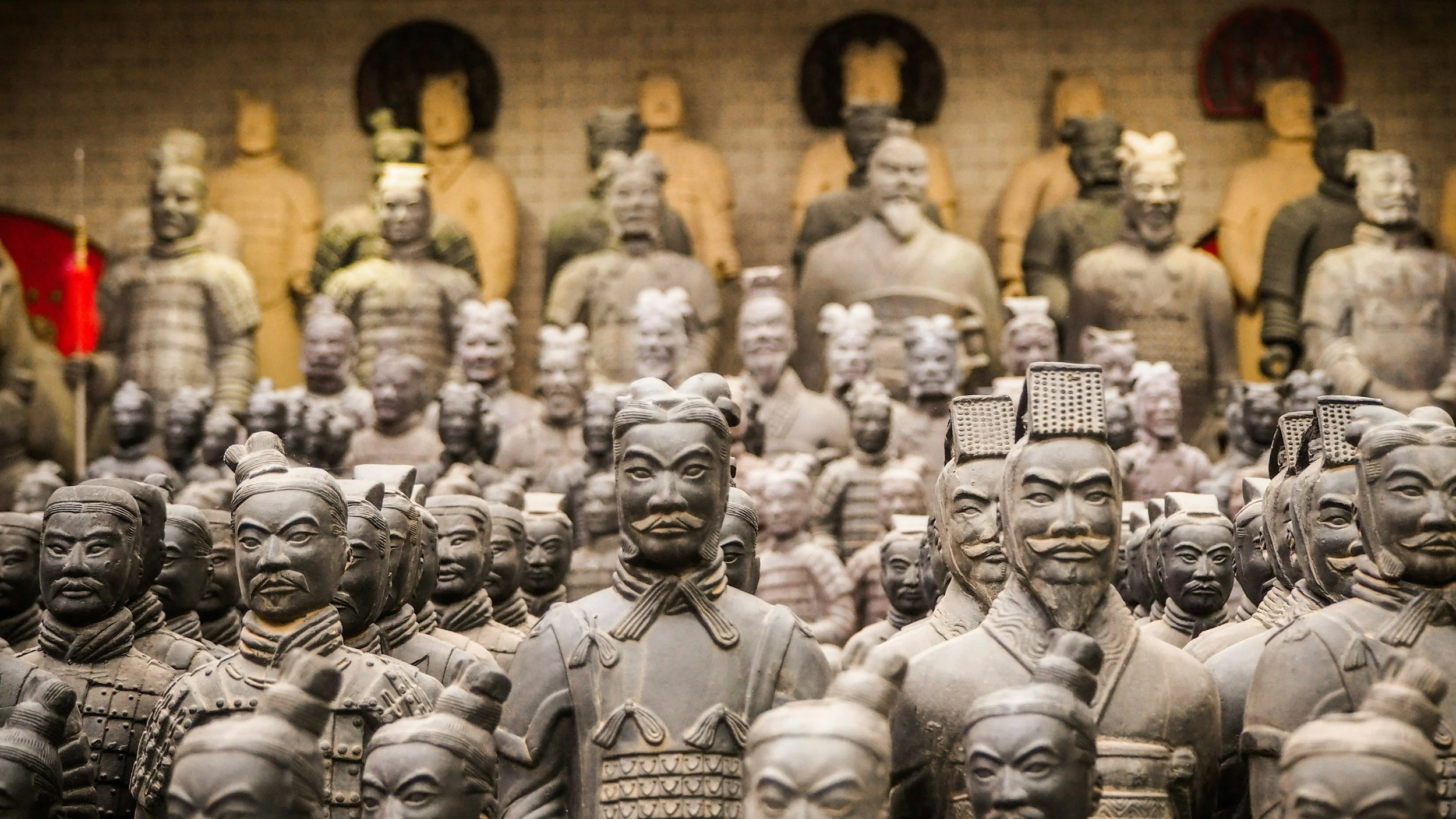 Close-up view of numerous small terracotta soldiers from the Terracotta Army, with larger statues in the background.