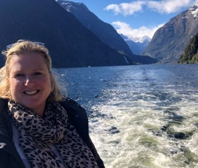 Woman on a boat with mountains and water in the background