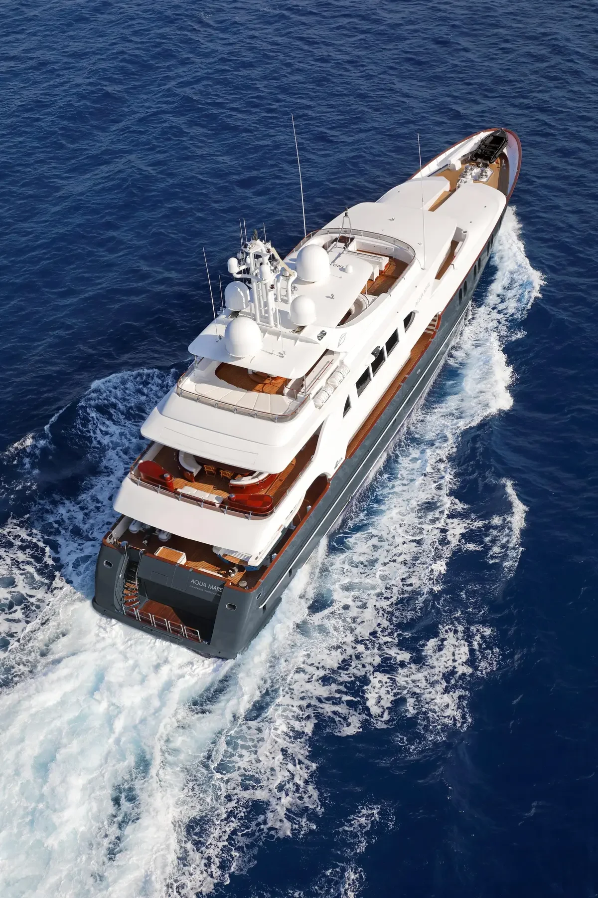 Aerial view of a luxury white yacht sailing on deep blue ocean water.
