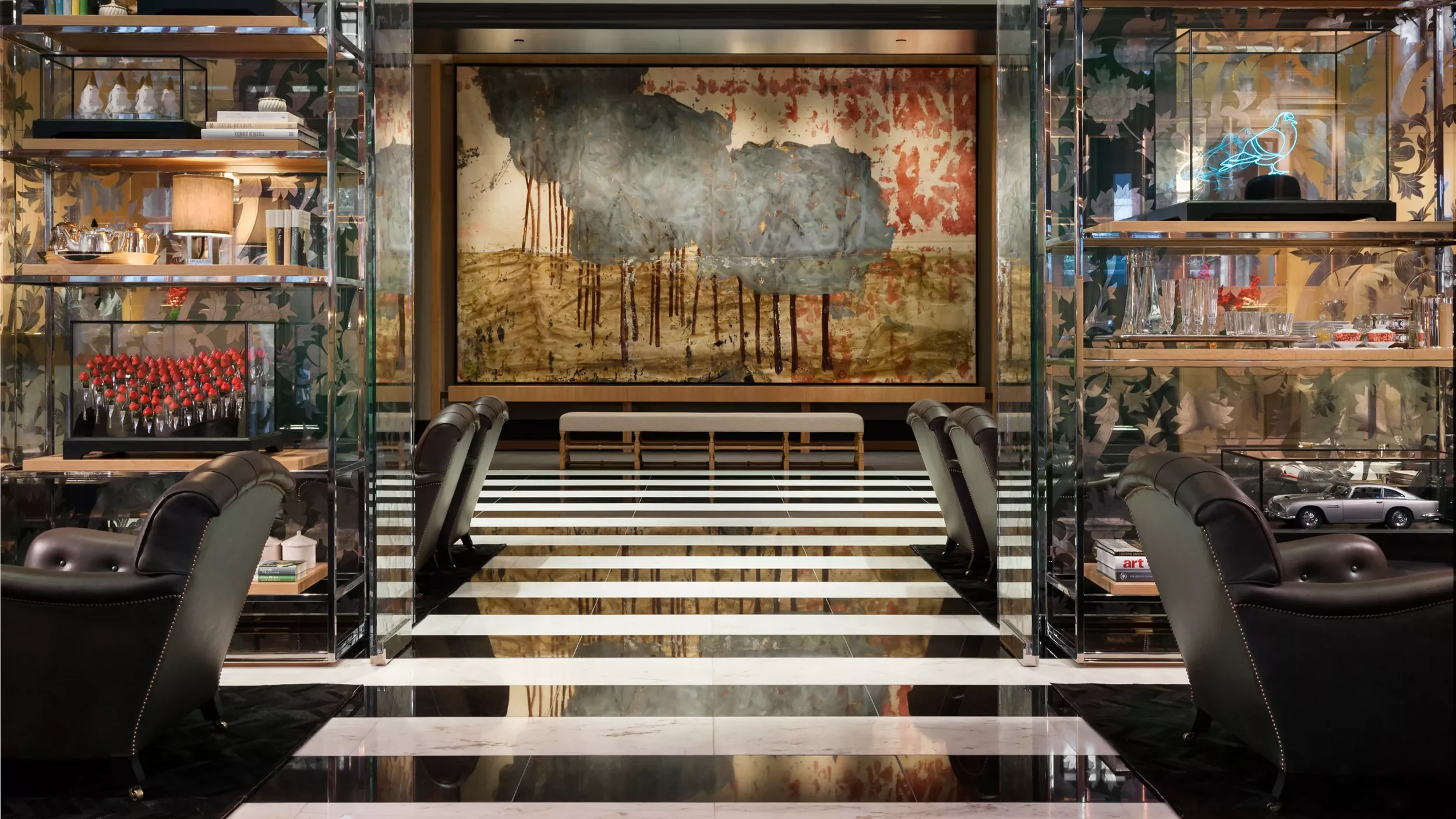 A luxurious room with black and white striped marble flooring, dark chairs, glass shelves with decorative items, a large landscape painting, and a geometric neon sign