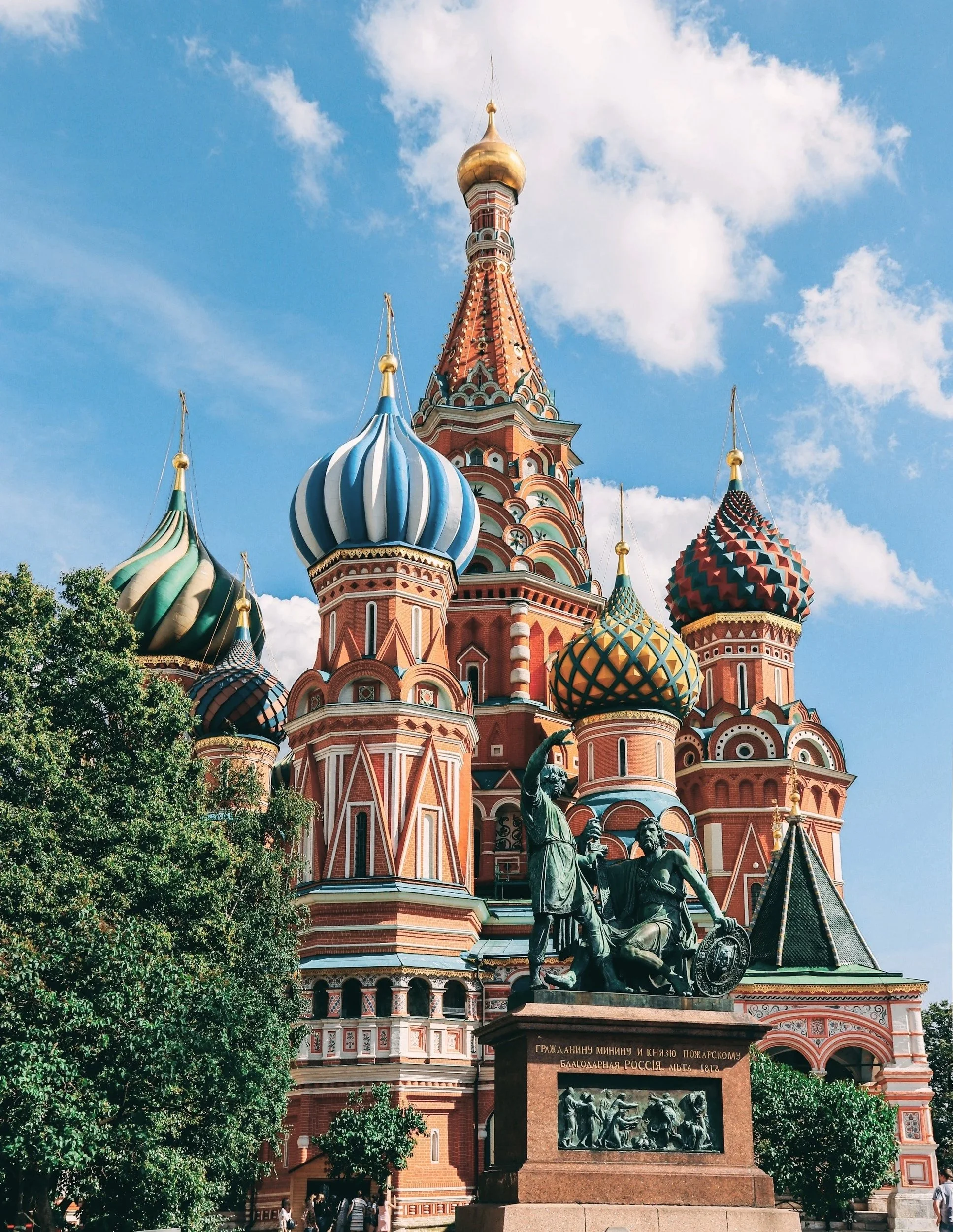 St. Basil's Cathedral with colorful onion domes in Red Square, Moscow, Russia, under a blue sky with clouds.