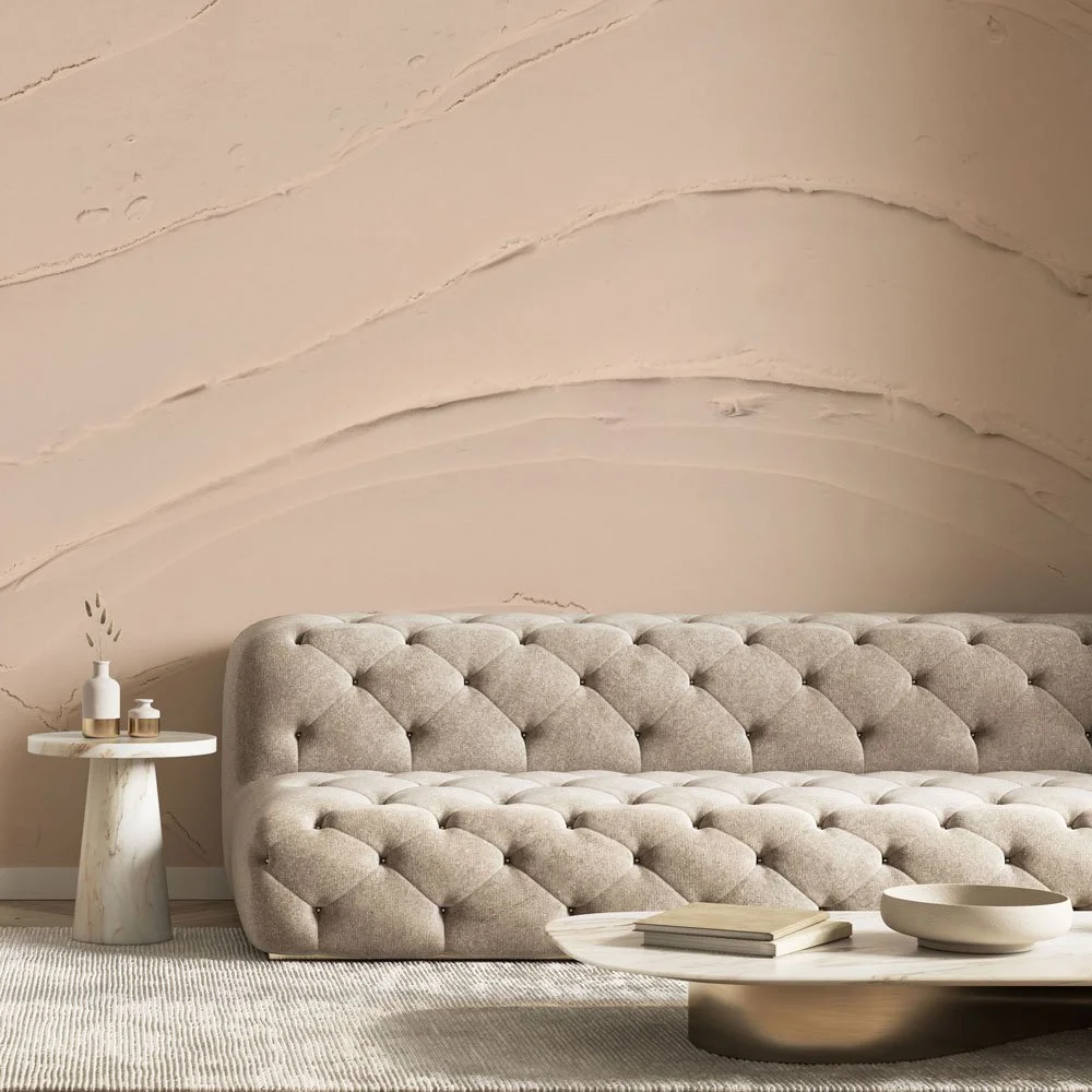 Neutral tufted sofa in a soft modern living room with a blush-toned plaster-textured wall from the Terrene wallcovering collection.