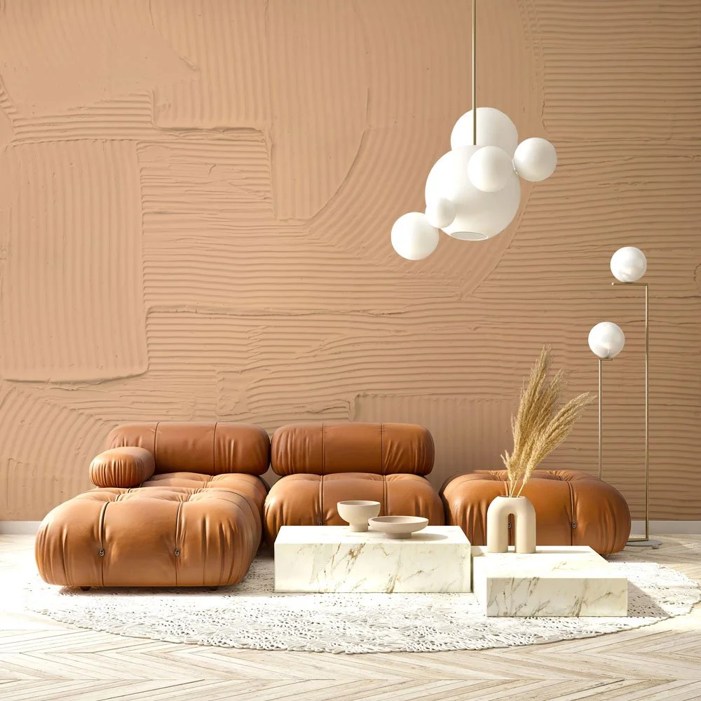 Sculptural terracotta-toned wallcovering with sweeping plaster textures, styled with mid-century modern leather lounge seating and marble coffee tables.