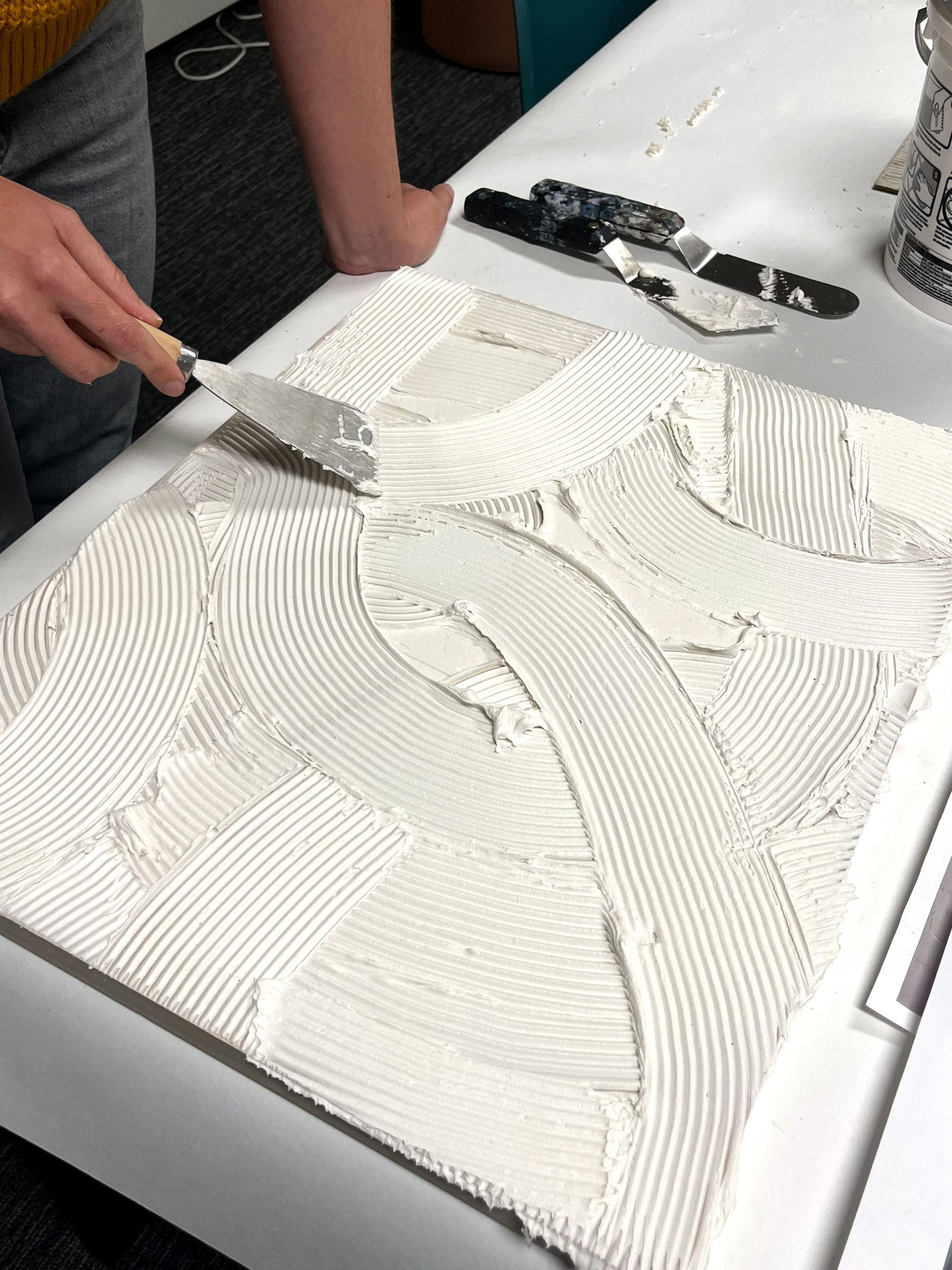 Hand applying sculptural plaster textures with a palette knife during the creation process of a wallcovering design from the Terrene collection.