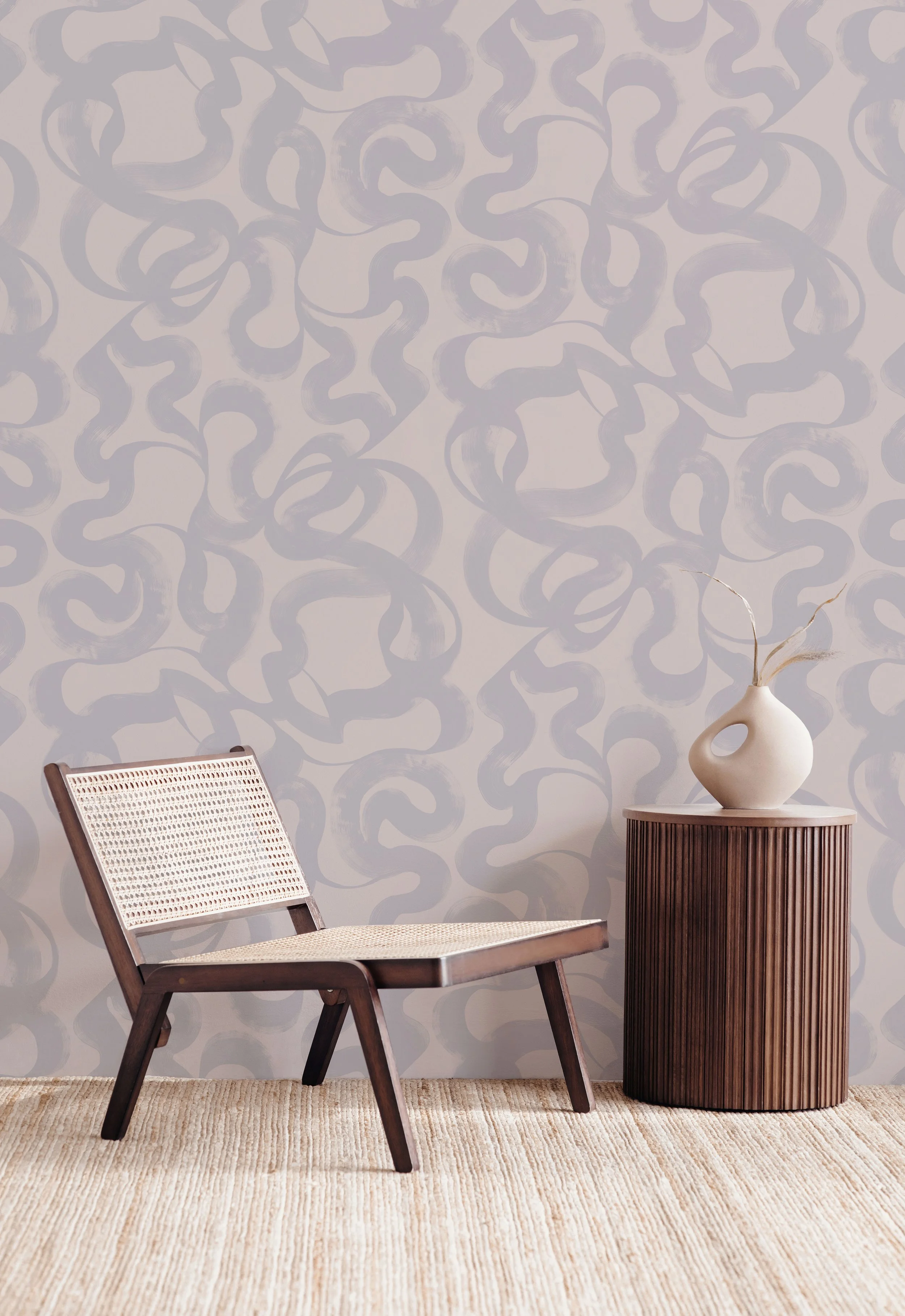 Muted lilac abstract brushstroke wallpaper with cane accent chair and fluted wood side table in modern interior