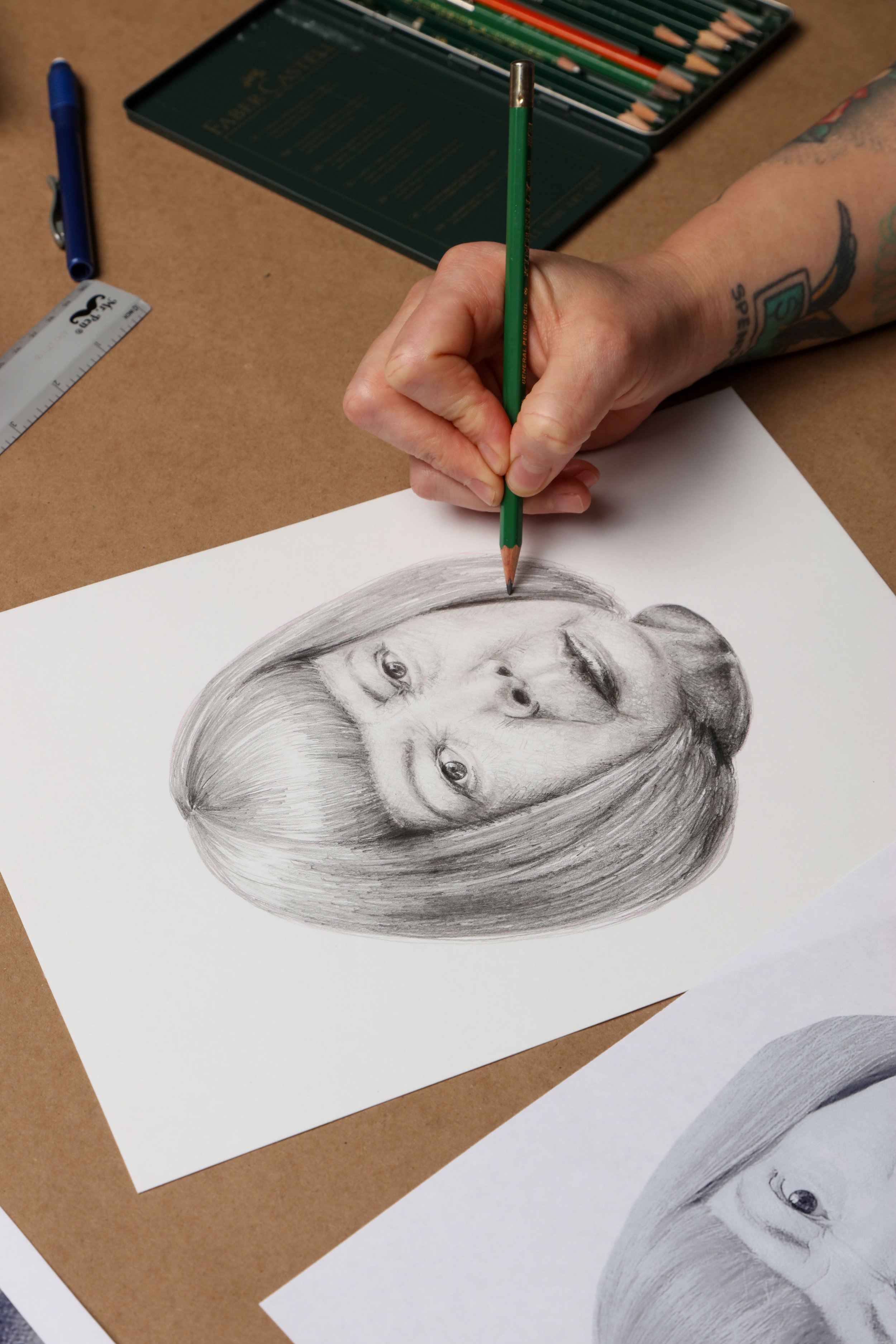 Close-up of a hand sketching a realistic pencil portrait of Yayoi Kusama, part of the Iconographic wallcovering development process for the Terry Crews collaboration with Astek