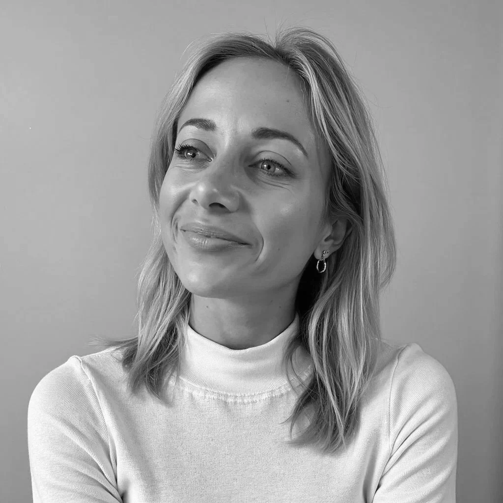 Black and white portrait of a woman with shoulder-length hair, wearing a turtleneck sweater, smiling softly and looking slightly to her right.