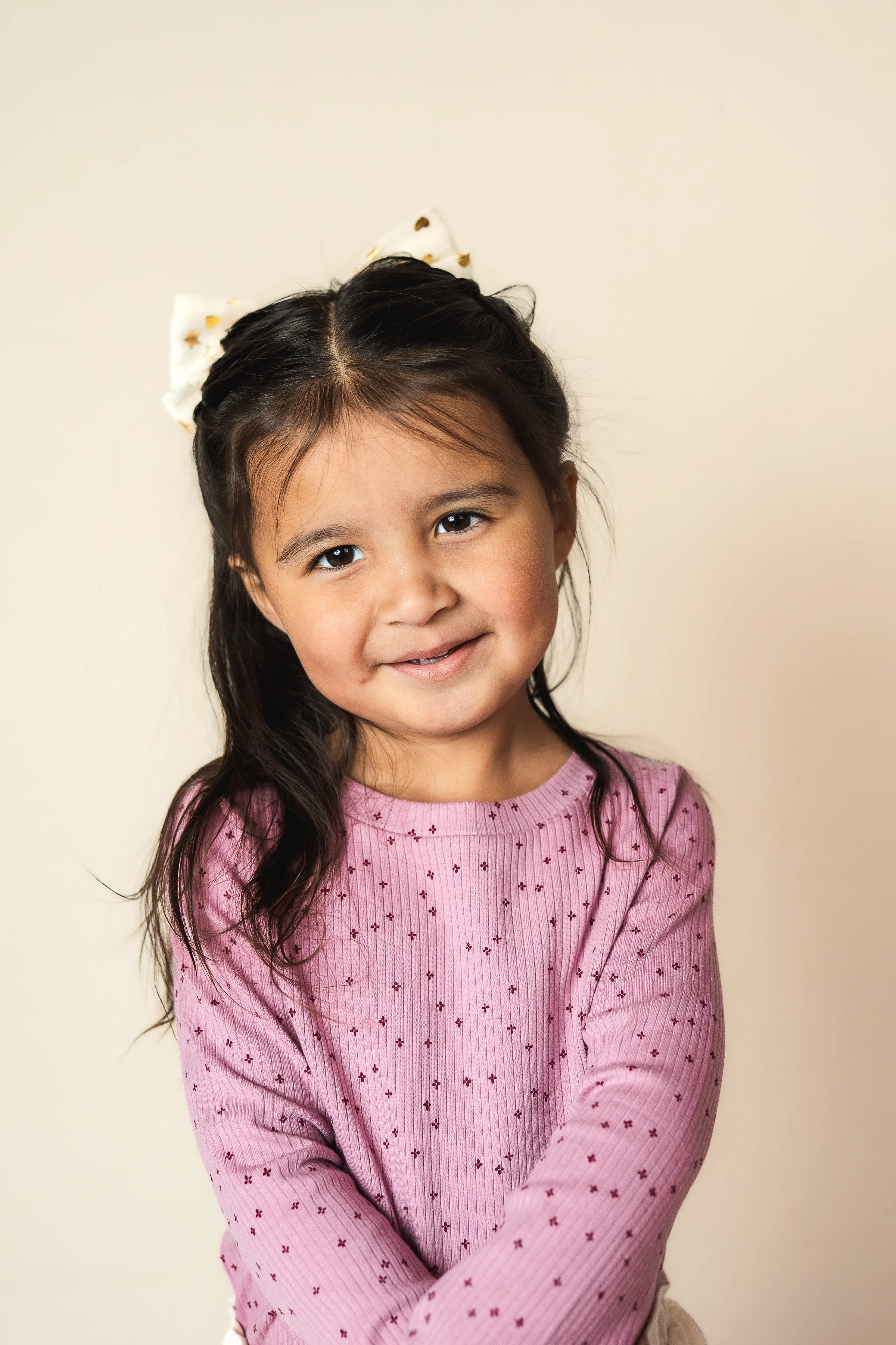 Child poses for fine art school photo on a cream background