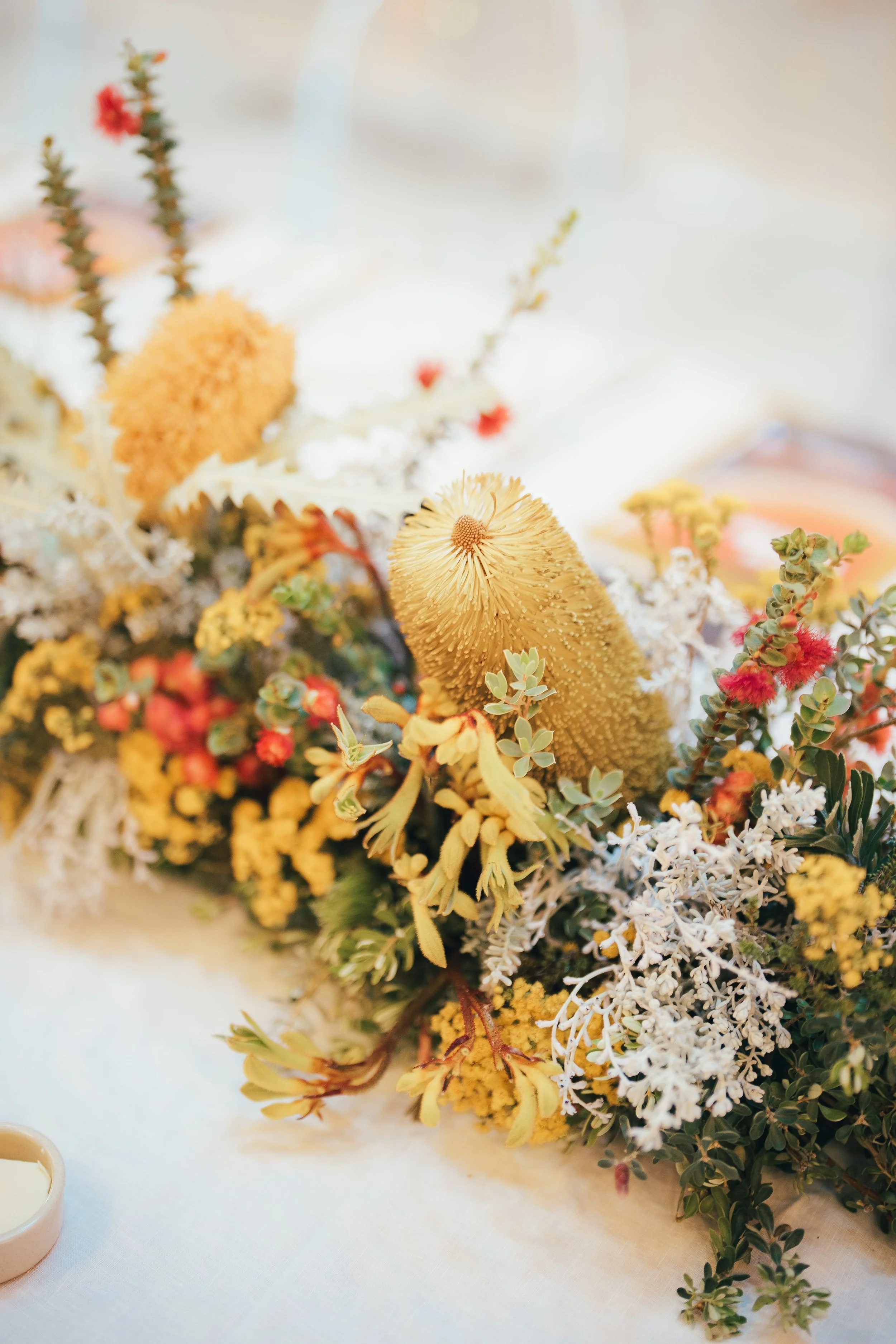 A colourful, West Australian native floral arrangement with a variety of flowers and greenery on a table.