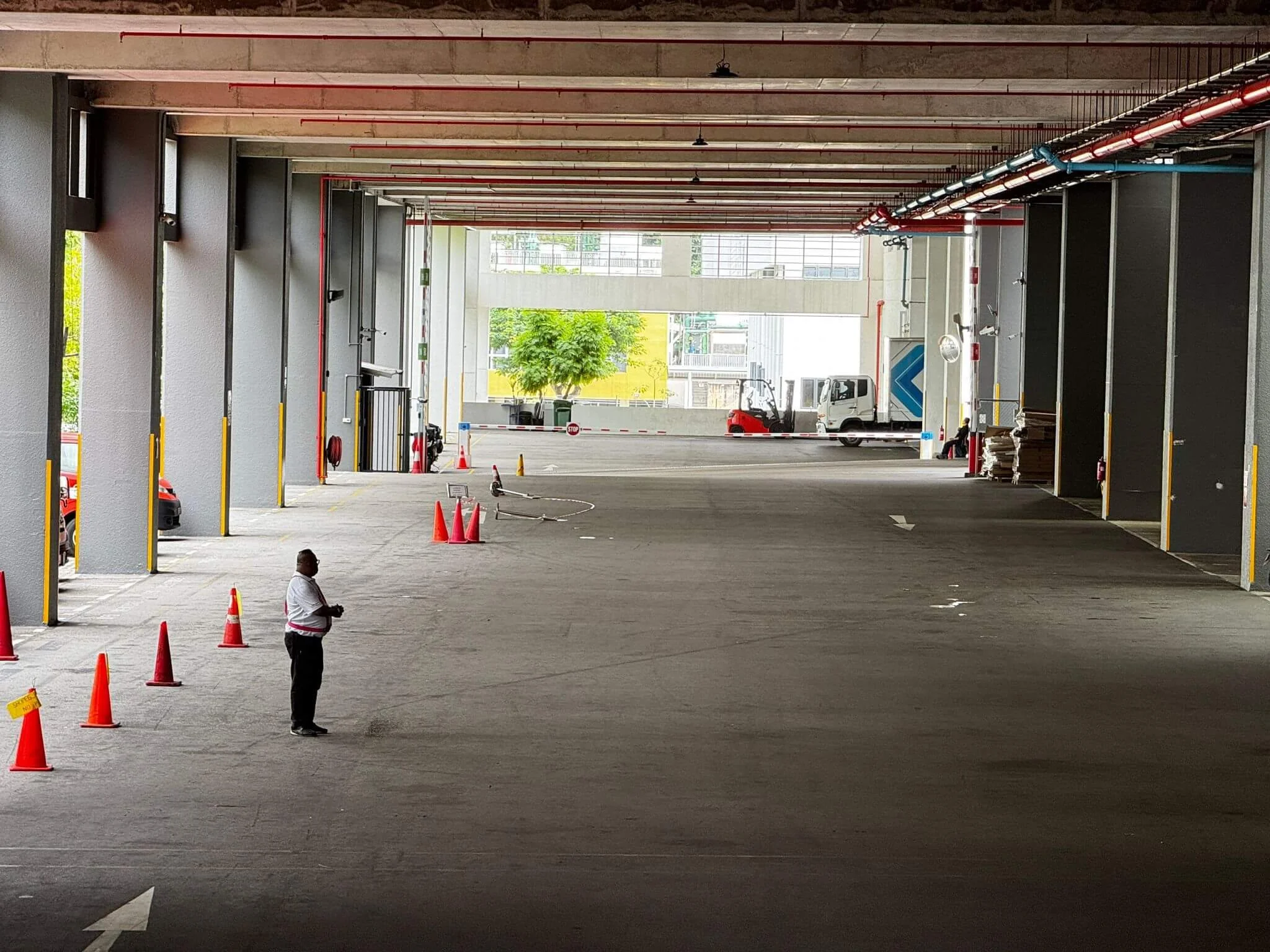 Underground parking area with cones, a person, and parked trucks and cars