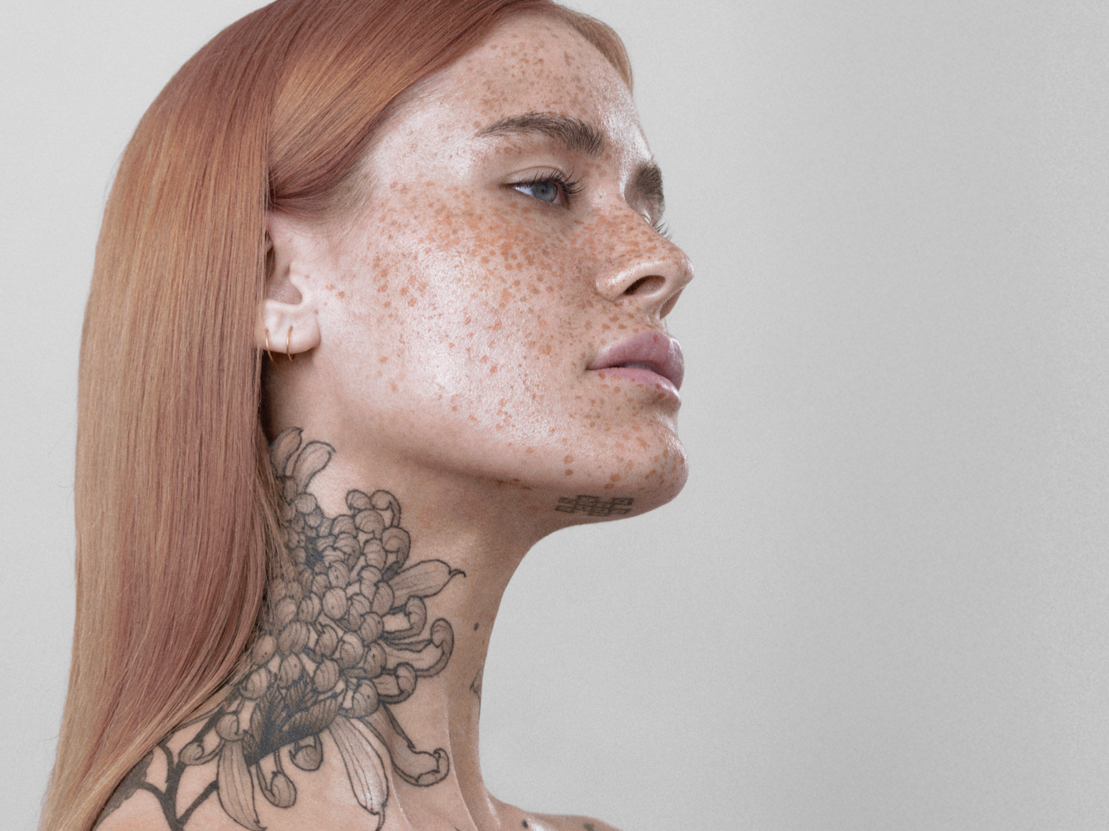 A side-by-side portrait of two women with freckles and red hair facing each other against a plain light background.