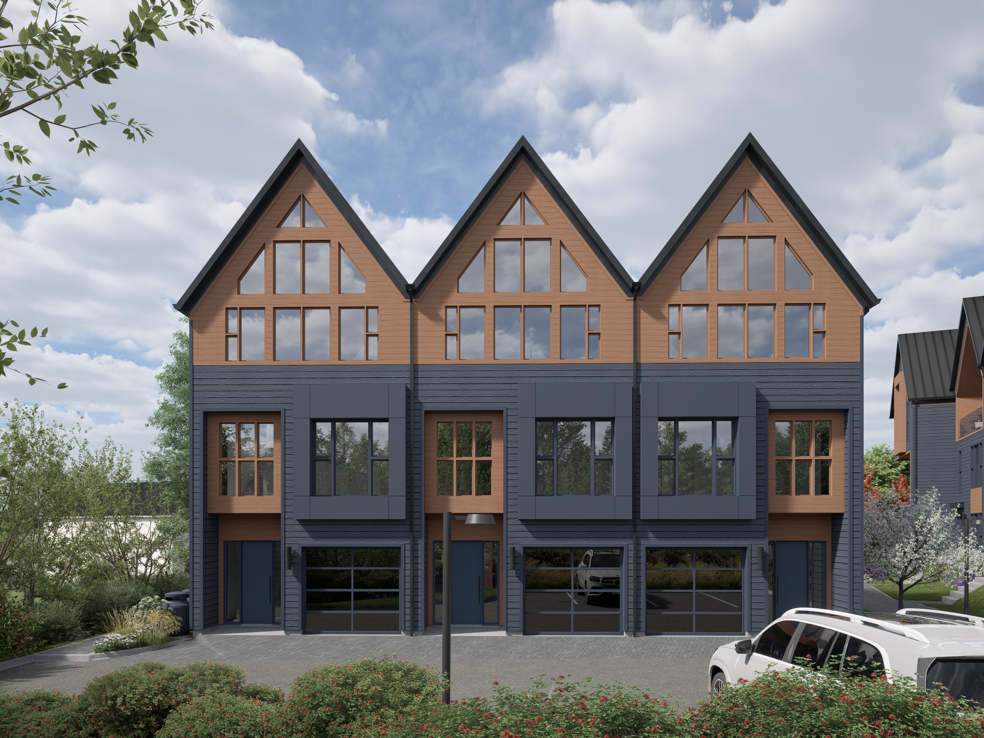 Modern multi-story row houses with a combination of black and natural wood exterior, large windows, small front parking area, surrounded by greenery and flowering bushes, under a partly cloudy sky.