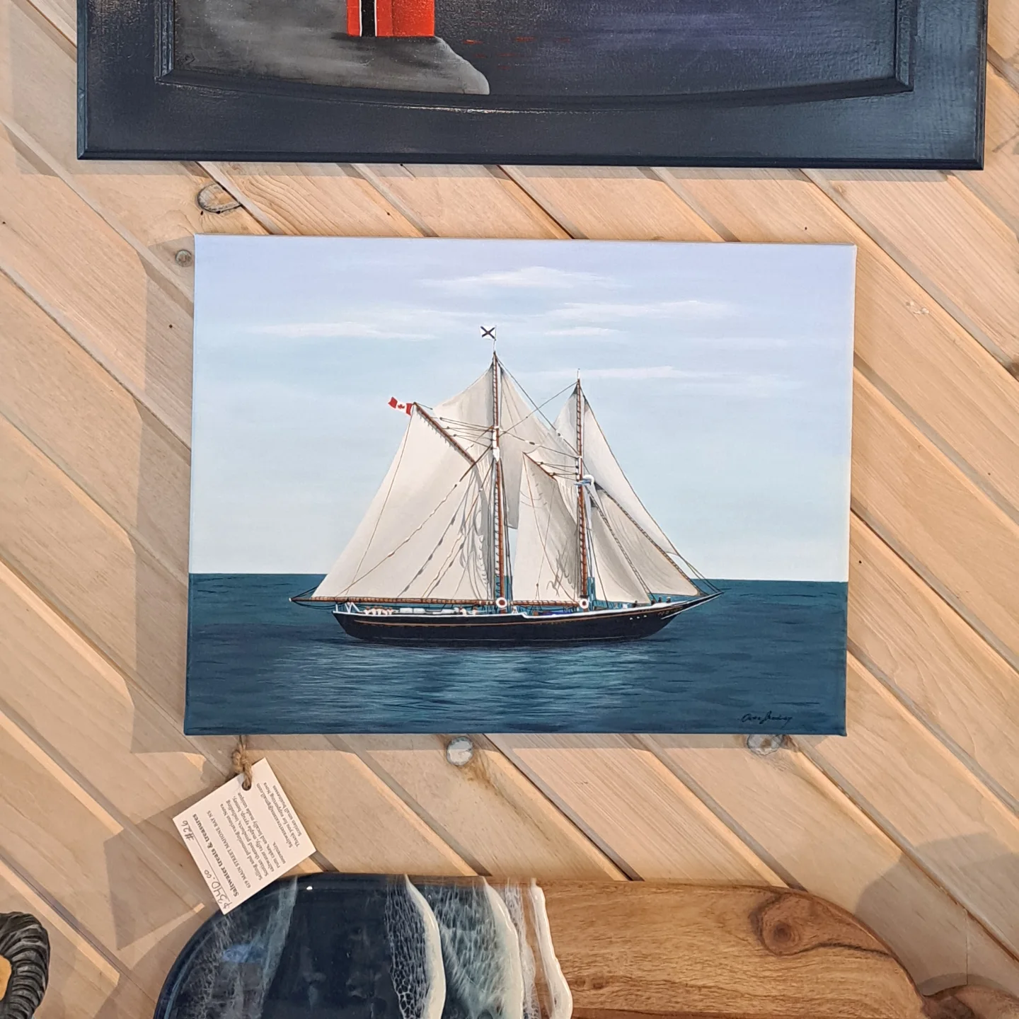 Painting of a sailing ship with multiple white sails on calm blue water, under a cloudy sky.