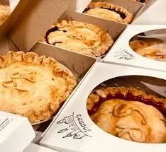 Multiple boxes of assorted pies with various flavors and toppings.